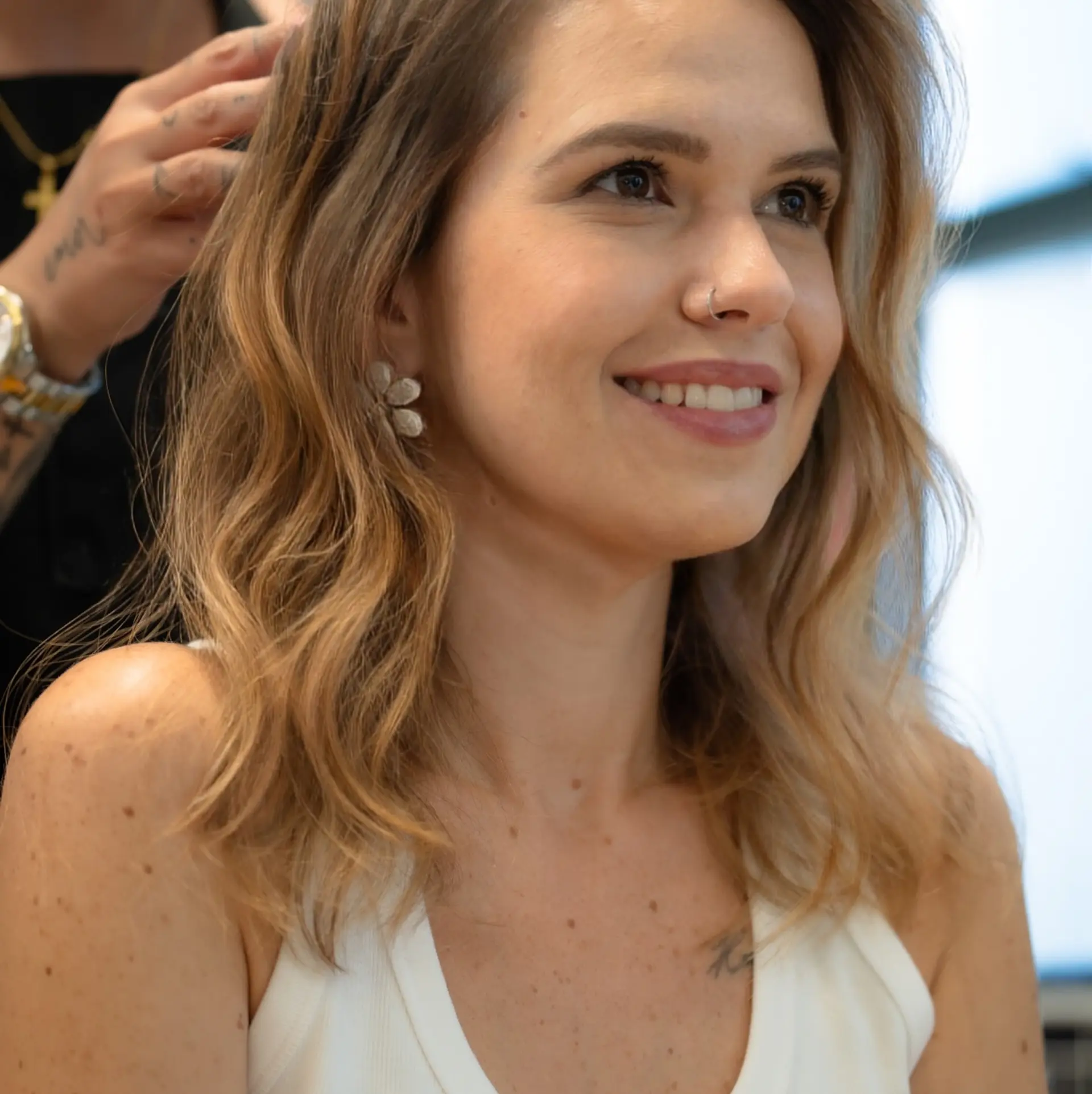 A medium-length cut styled in loose, soft waves with warm honey blonde dimensional highlights. 1