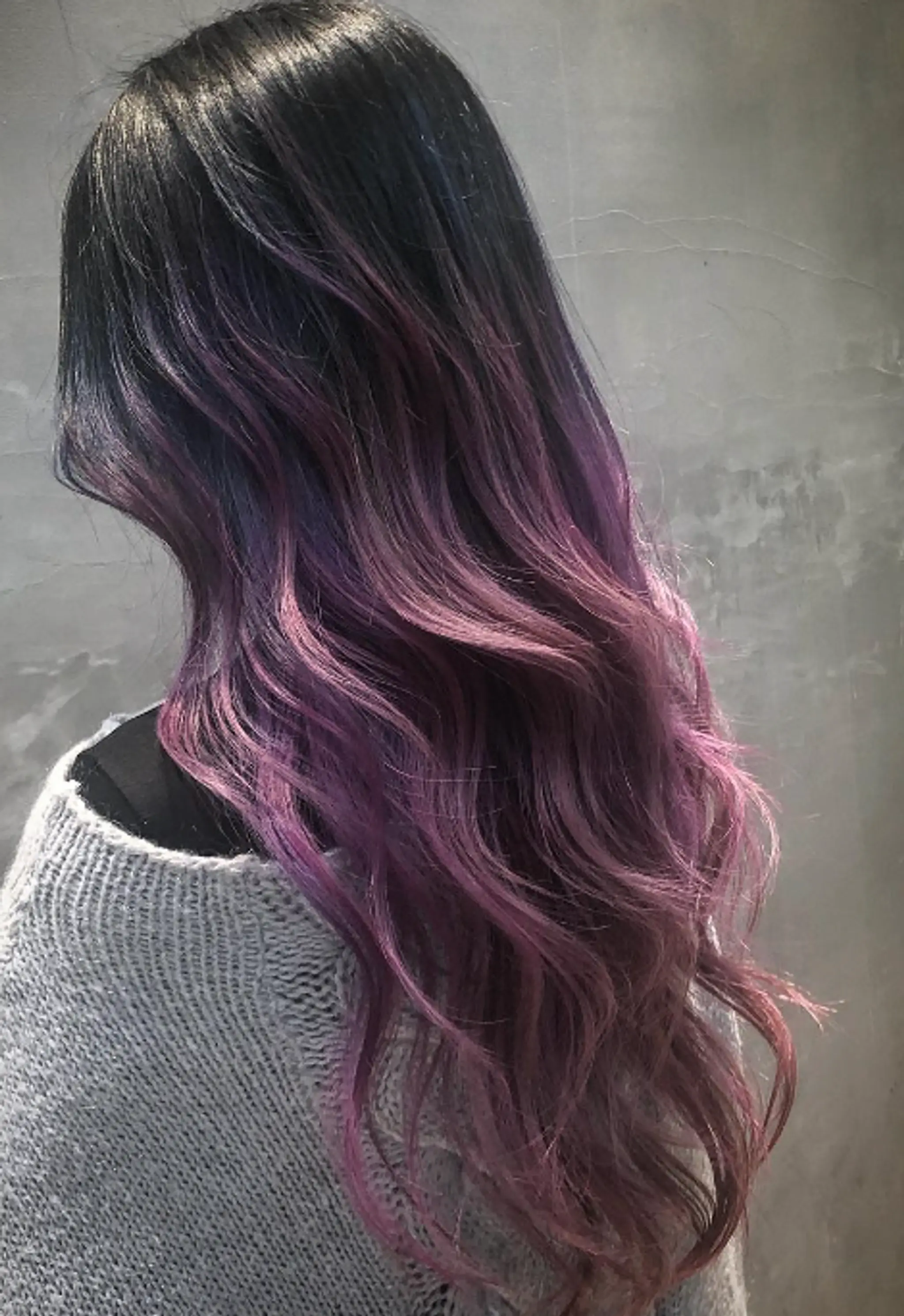 Long, wavy hair with a black-to-purple ombre effect, transitioning into pastel lilac tips.