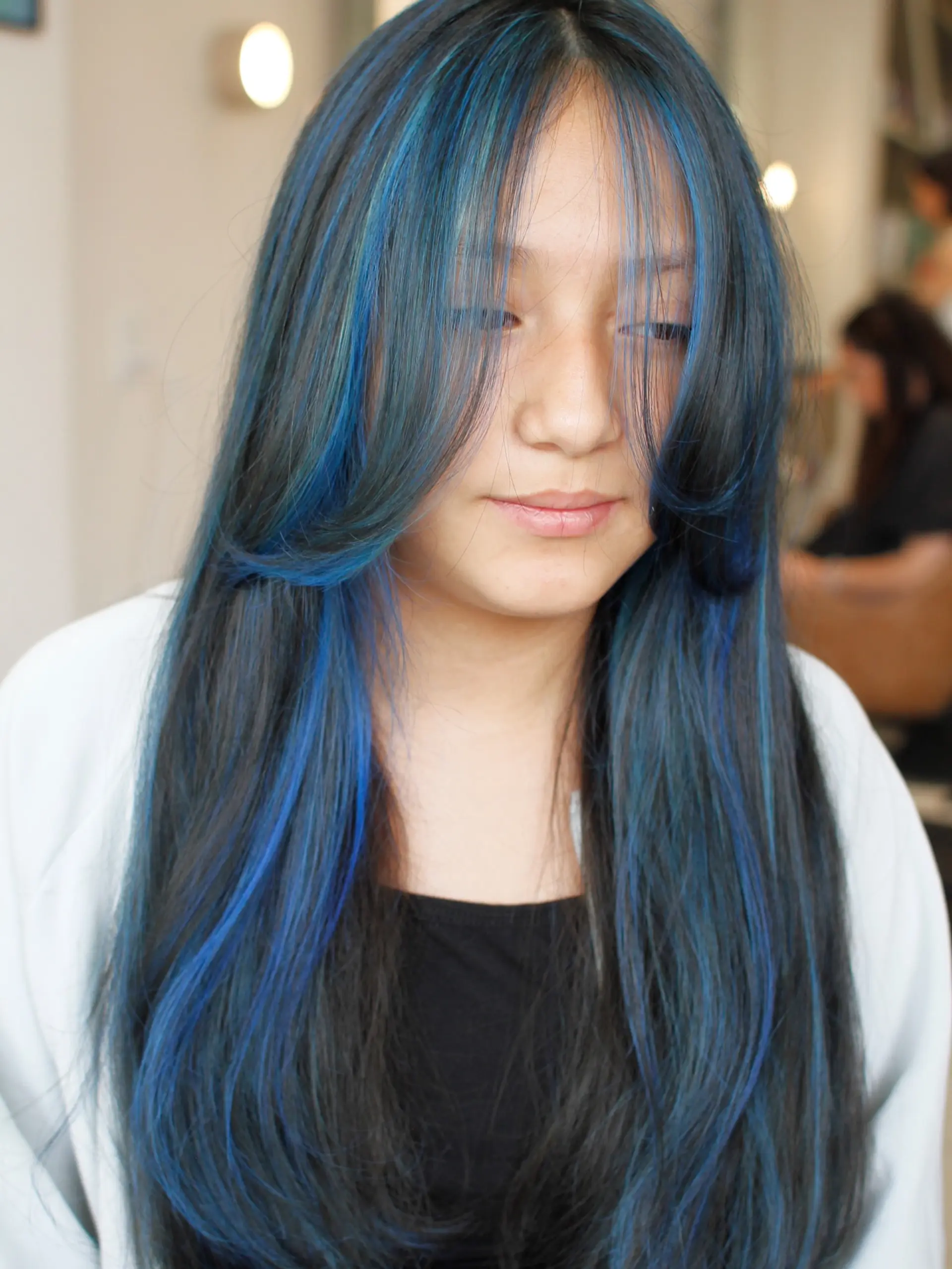 Long dark hair highlighted with electric and oceanic blue tones, styled with face-framing curtain layers. 1