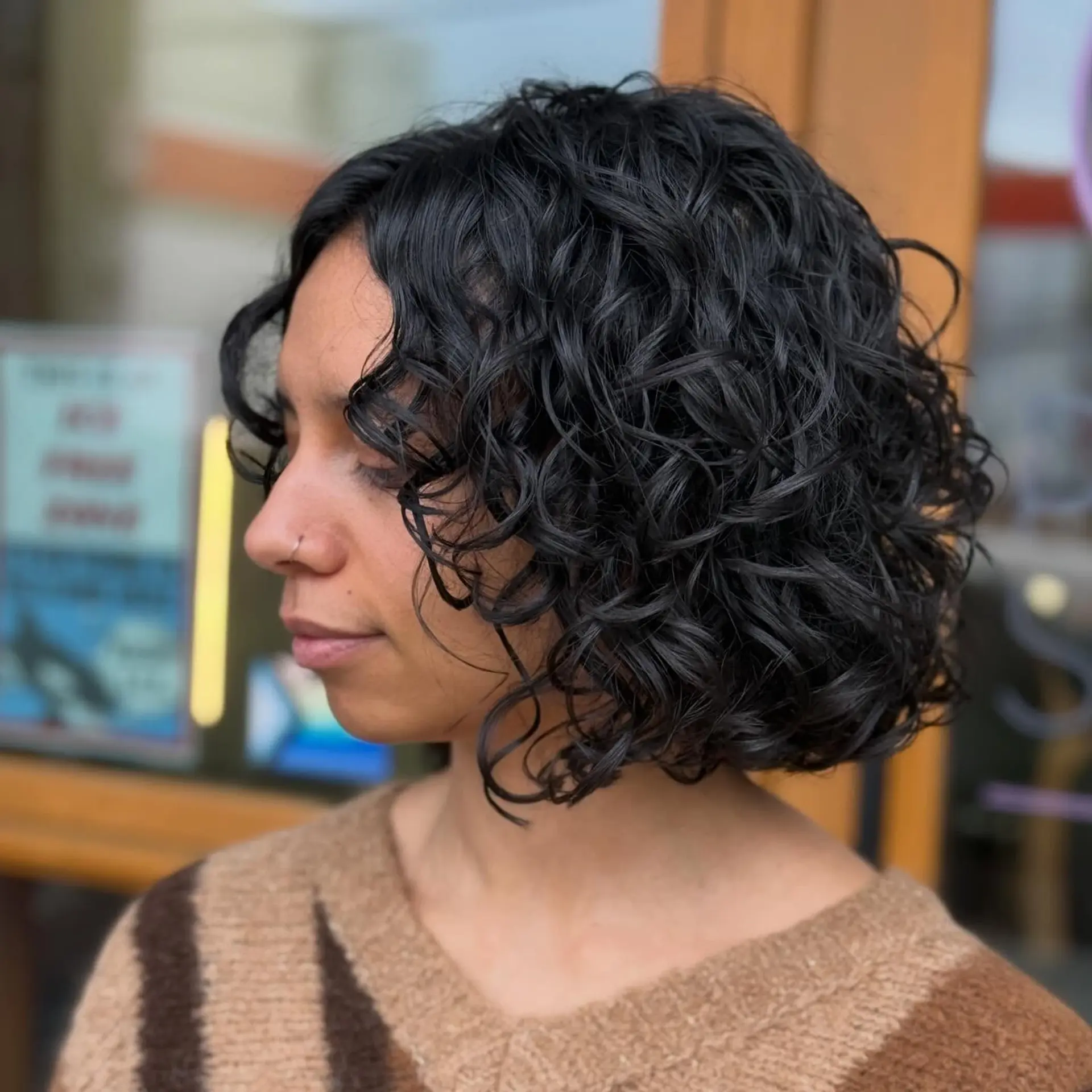 A chin-length curly bob cut with subtle layers to release weight and enhance bounce, featuring defined, glossy ringlets and natural movement. 1