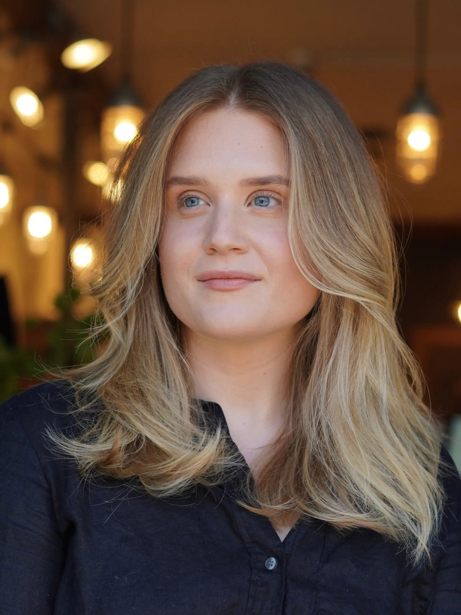 Lived-in warm blonde hair with long face-framing layers and soft blown-out styling. 1