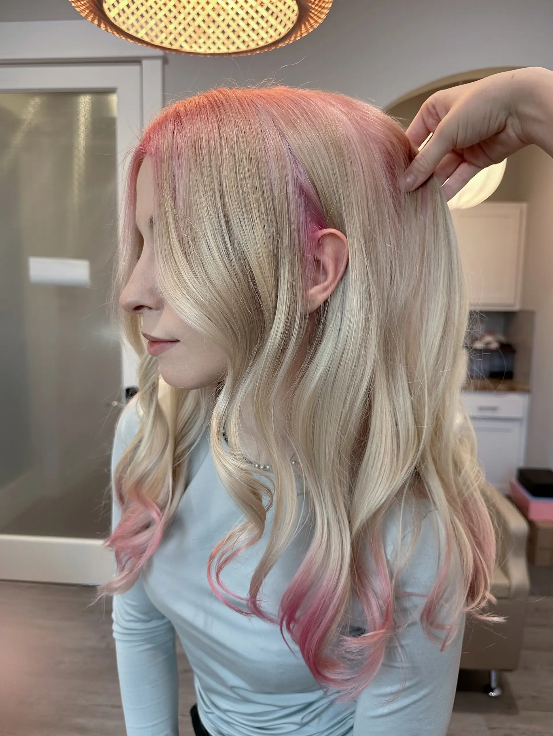 Long, flowing platinum blonde hair styled in soft waves, complemented by a seamless pastel pink root melt that gradually blends into the blonde, with hints of pink also visible towards the ends. 2