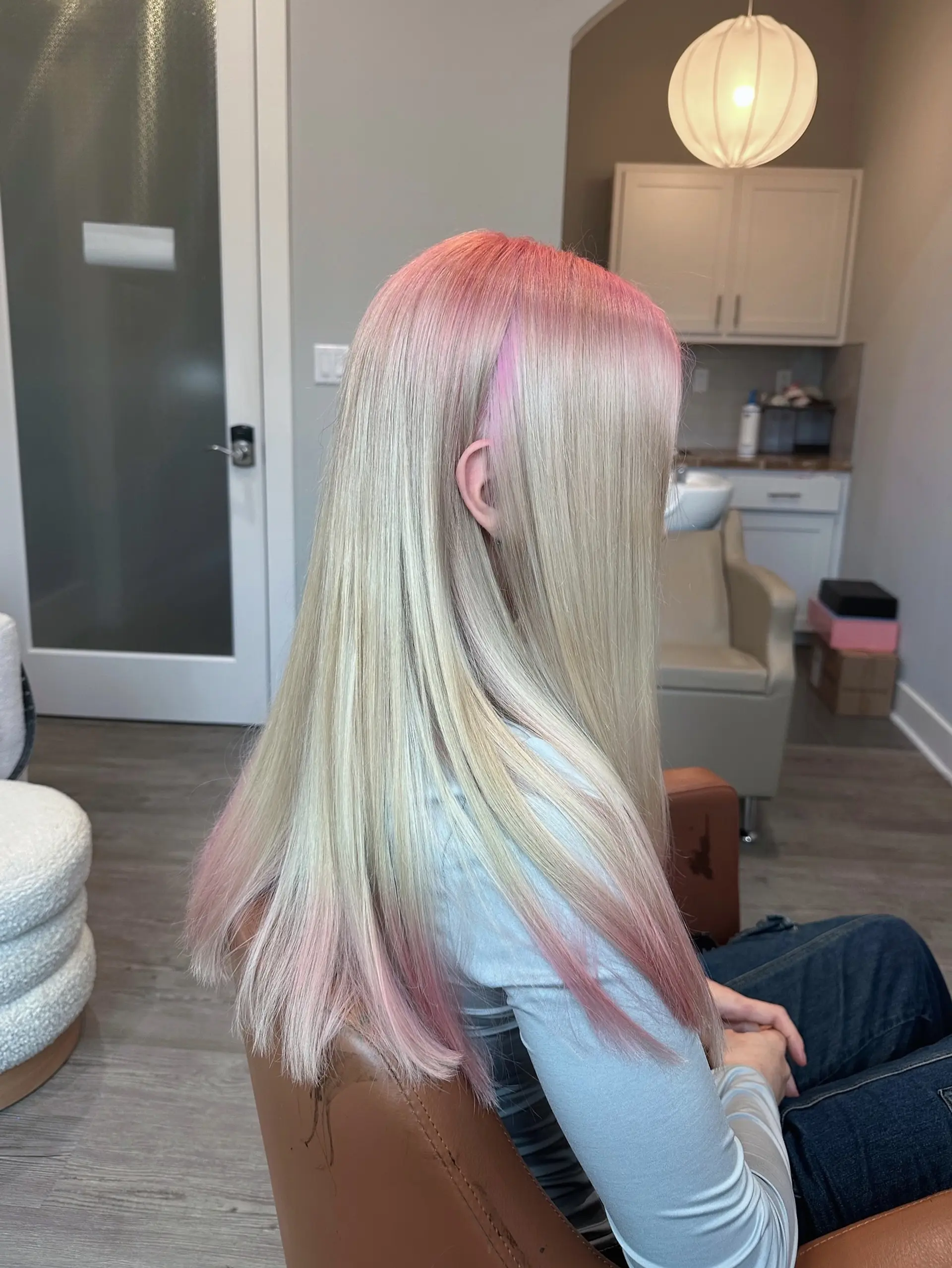 Long, flowing platinum blonde hair styled in soft waves, complemented by a seamless pastel pink root melt that gradually blends into the blonde, with hints of pink also visible towards the ends. 1