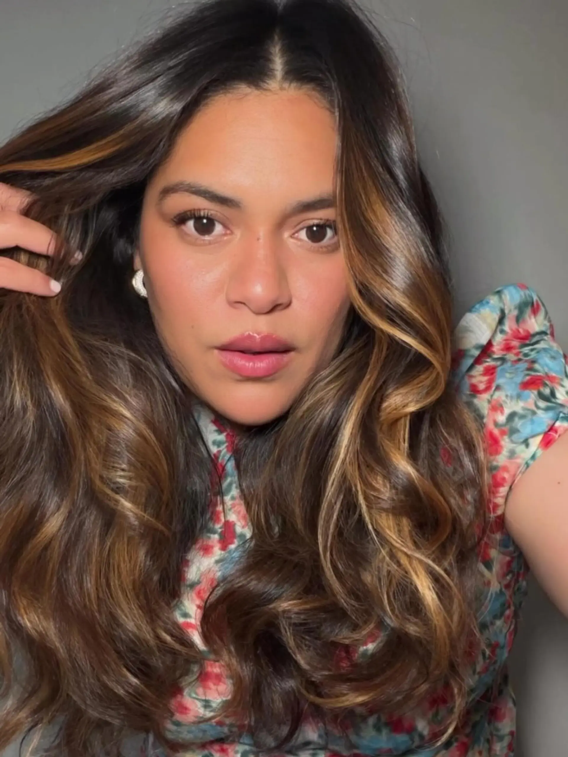 Voluminous, flowing waves with a dark brunette base accented by dimensional warm caramel ribbons and a high-gloss finish. 1