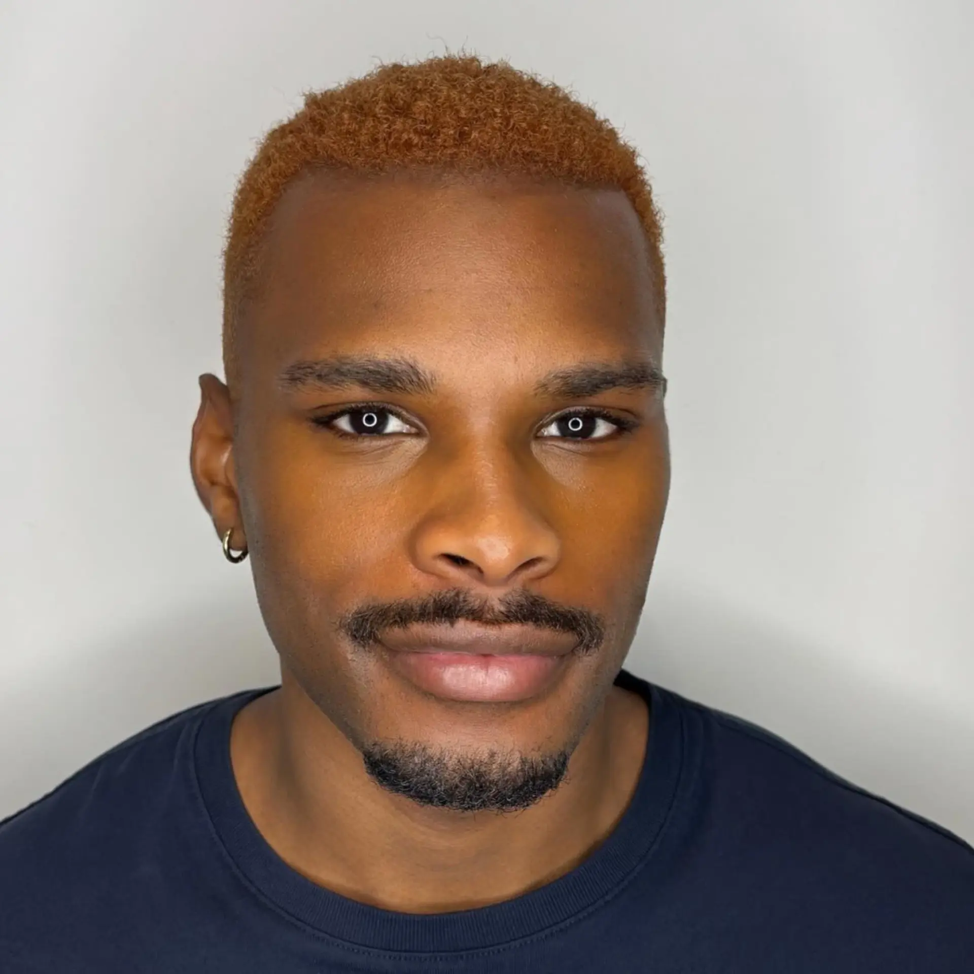 A closely cropped coily buzz cut colored in an all-over warm copper tone. 1