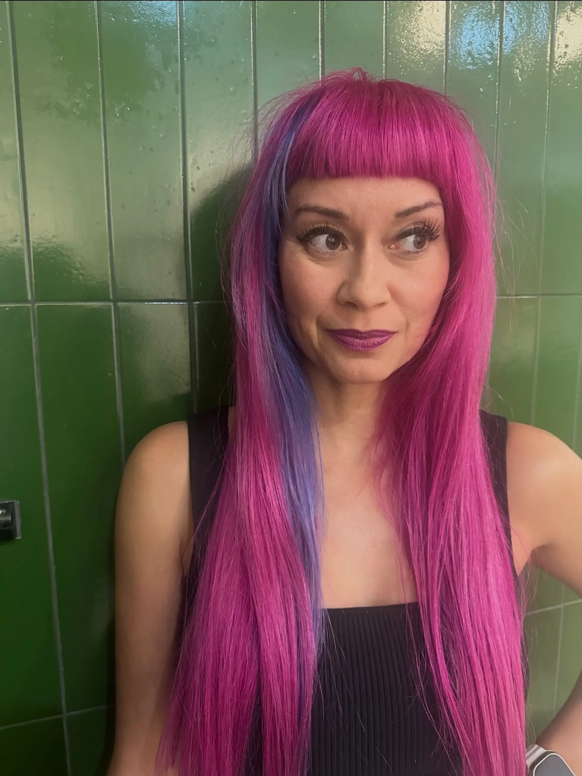 Straight, vibrant magenta hair styled long with blunt baby bangs and a contrasting purple peekaboo section. 1