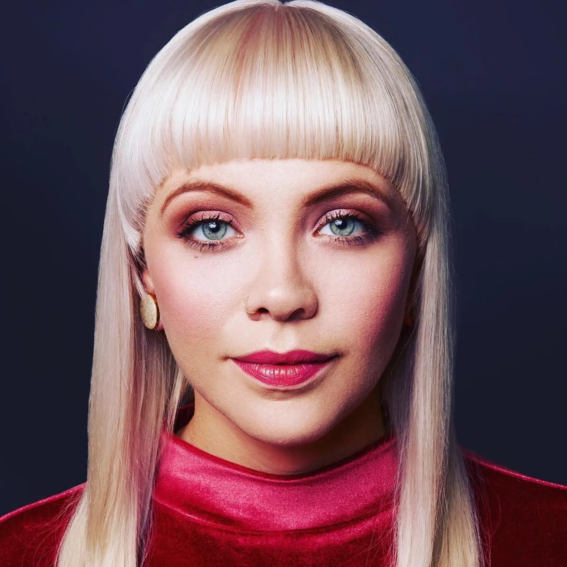 A sleek, platinum blonde look featuring sharp, straight-across blunt bangs and smooth face-framing layers. 1