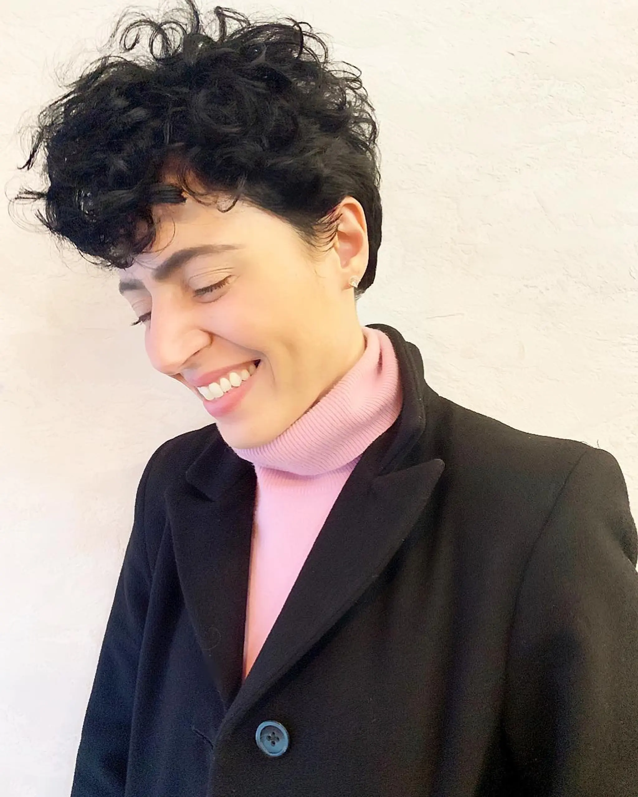 A beautifully short curly crop with natural volume, particularly around the crown and fringe areas. The black color intensifies the depth and shine of the curls, creating a chic and effortless look.
