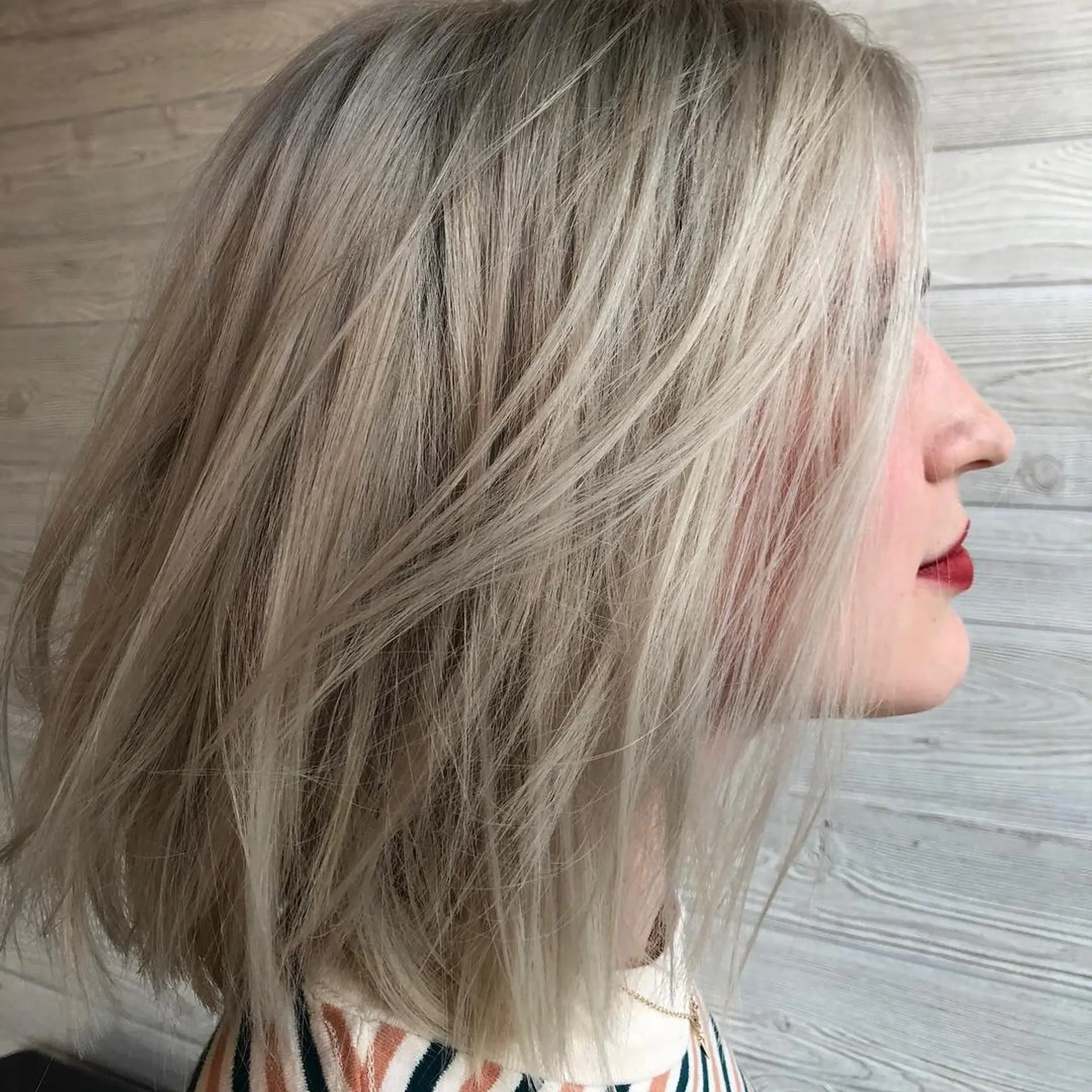 A medium-length textured ash blonde lob featuring soft, wispy layers and piecey styling. 1