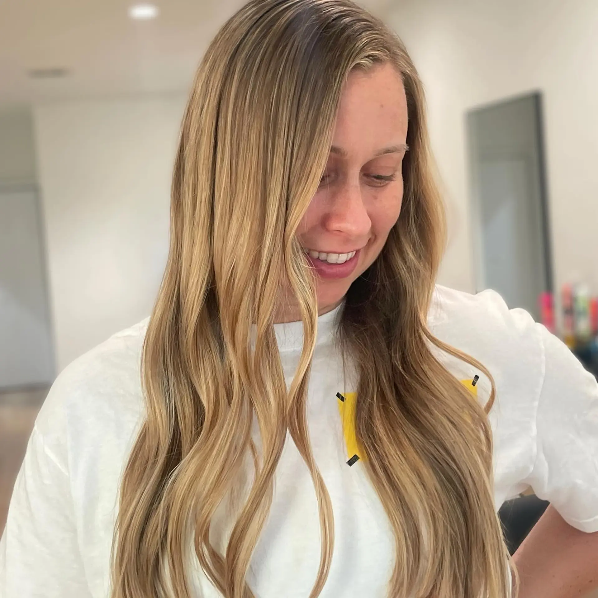 Long hair featuring warm blonde freehand balayage styled with relaxed, flowing waves. 1