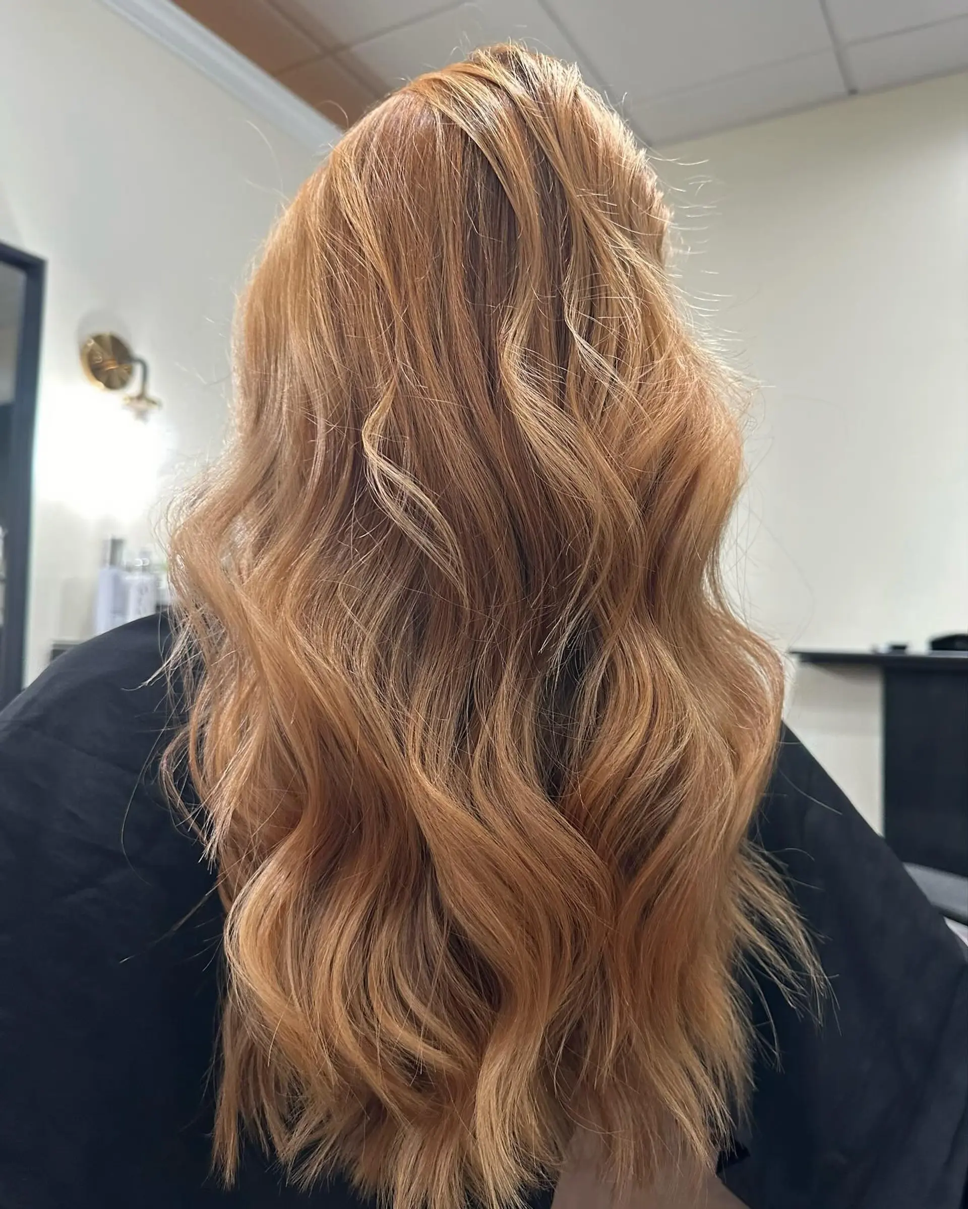 Long warm strawberry blonde hair styled in effortless, dimensional waves. 1