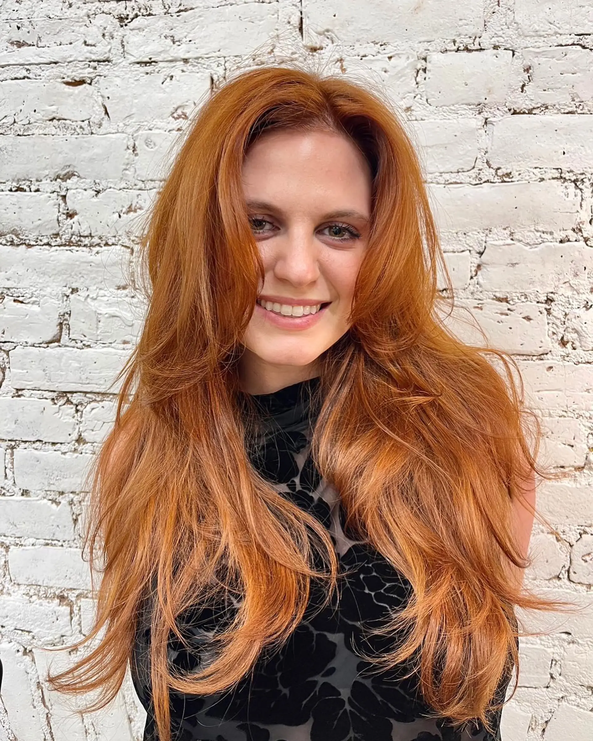 Vibrant copper-red long hair styled with soft face-framing layers and voluminous feathered ends. 1