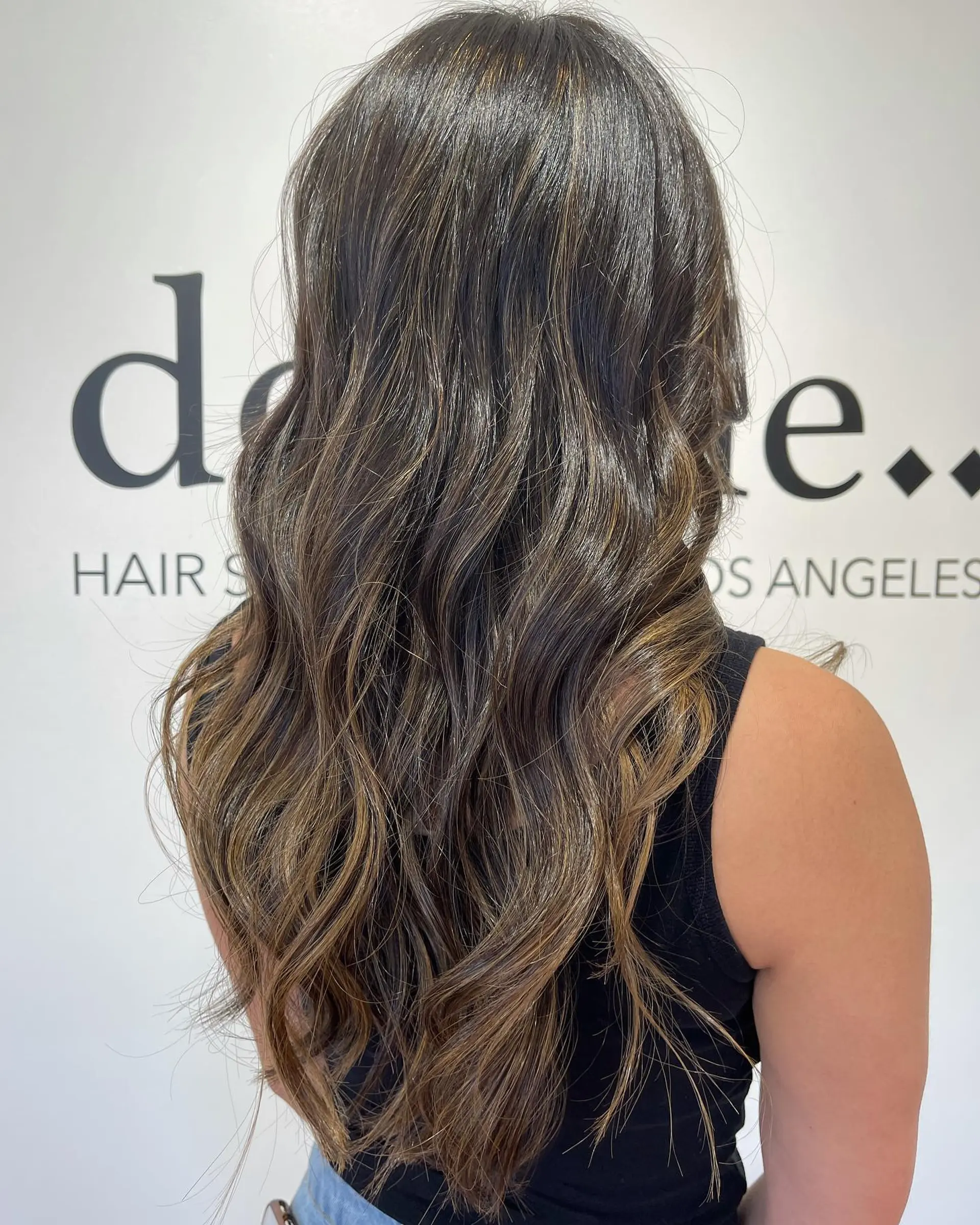 Long brunette hair styled in loose beach waves with dimensional caramel highlights. 1