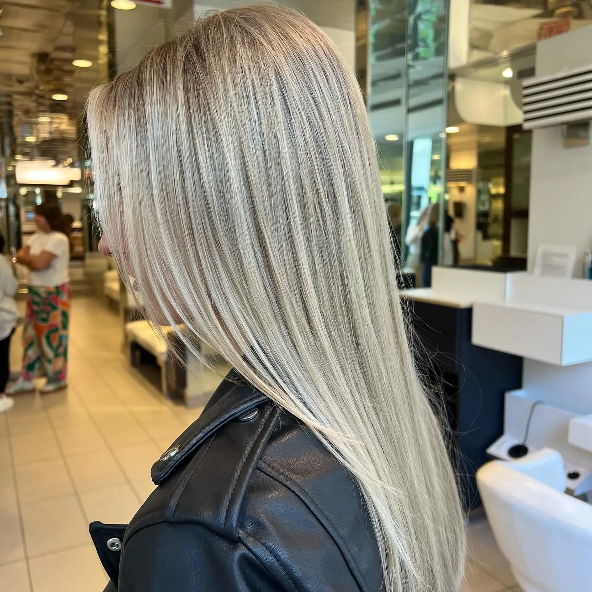 A sleek, long straight hairstyle featuring luminous cool-toned blonde highlights with an ultra-smooth finish. 1