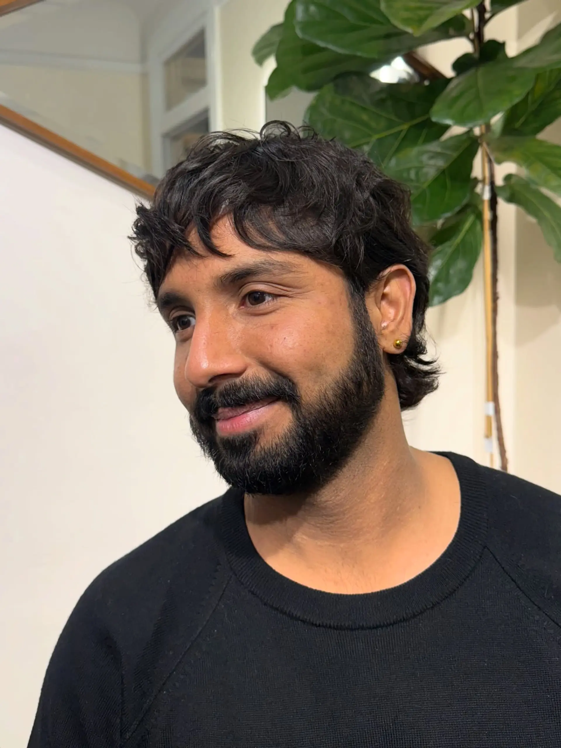A textured short wavy cut styled forward with piecey fringe and a groomed beard. 1