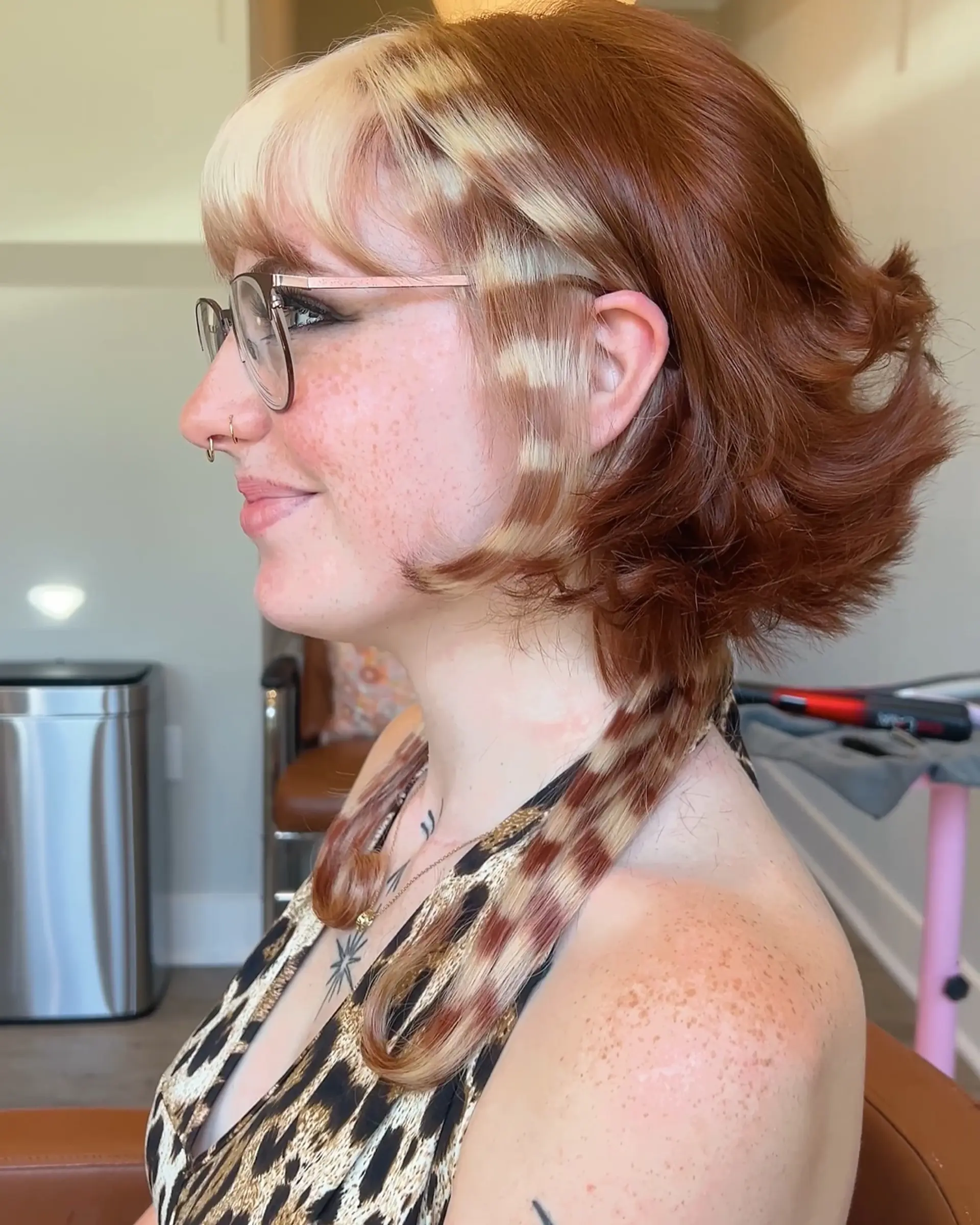 A choppy, layered short shag haircut with face-framing bangs, styled with defined waves. The hair is colored with a creative leopard print design, combining auburn and light blonde tones, including unique patterned strands. 1