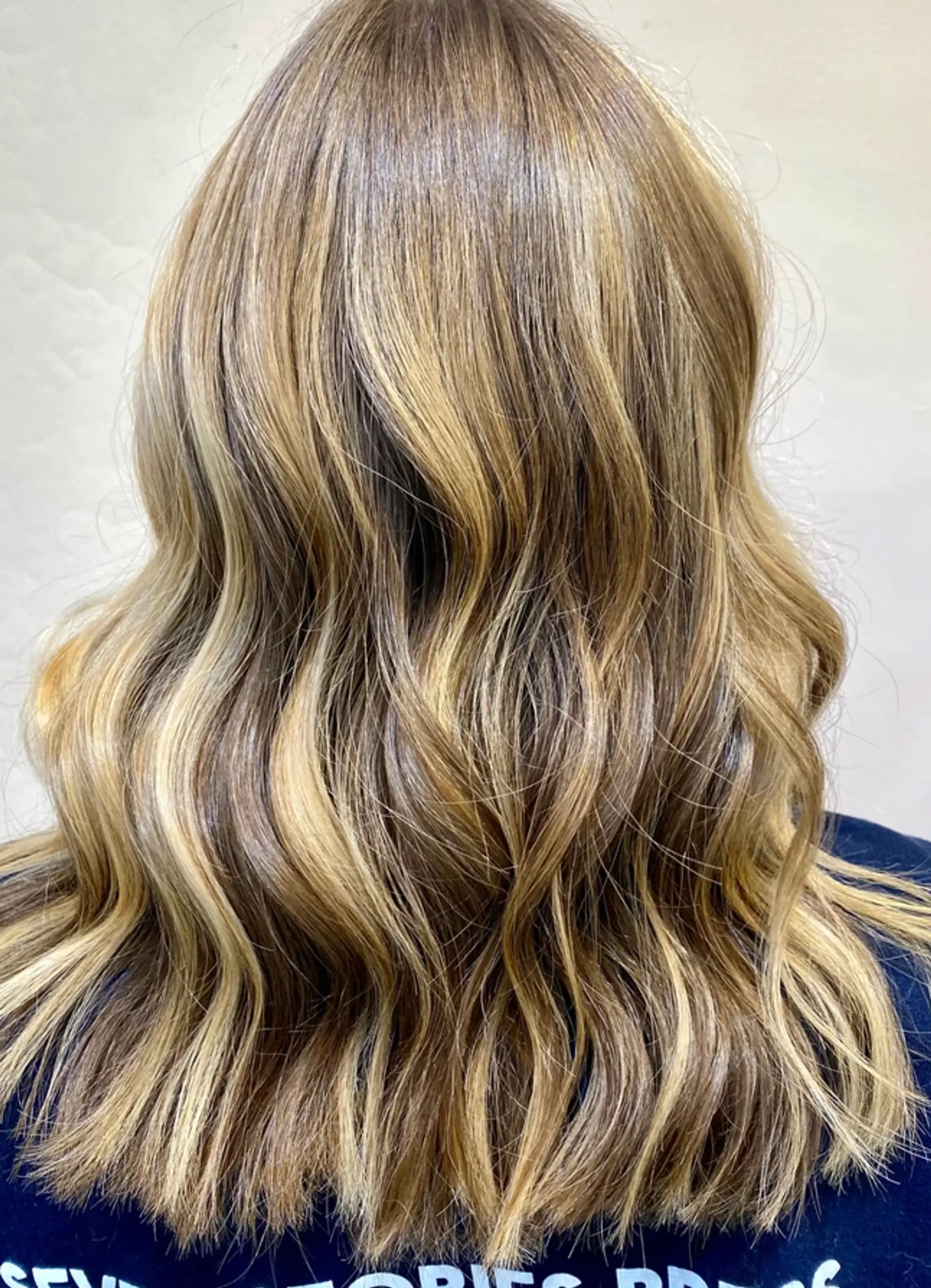 Medium-length wavy hair with soft, natural waves and sun-kissed highlights, creating a casual yet elegant look.