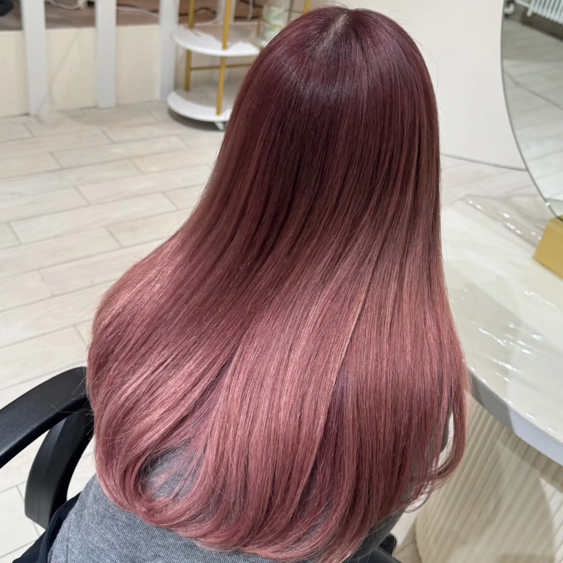 Long, sleek hairstyle with a beautiful ombre transition from rich rose gold at the roots to soft pink at the tips. The hair is straight and glossy, creating an elegant and modern look. 1