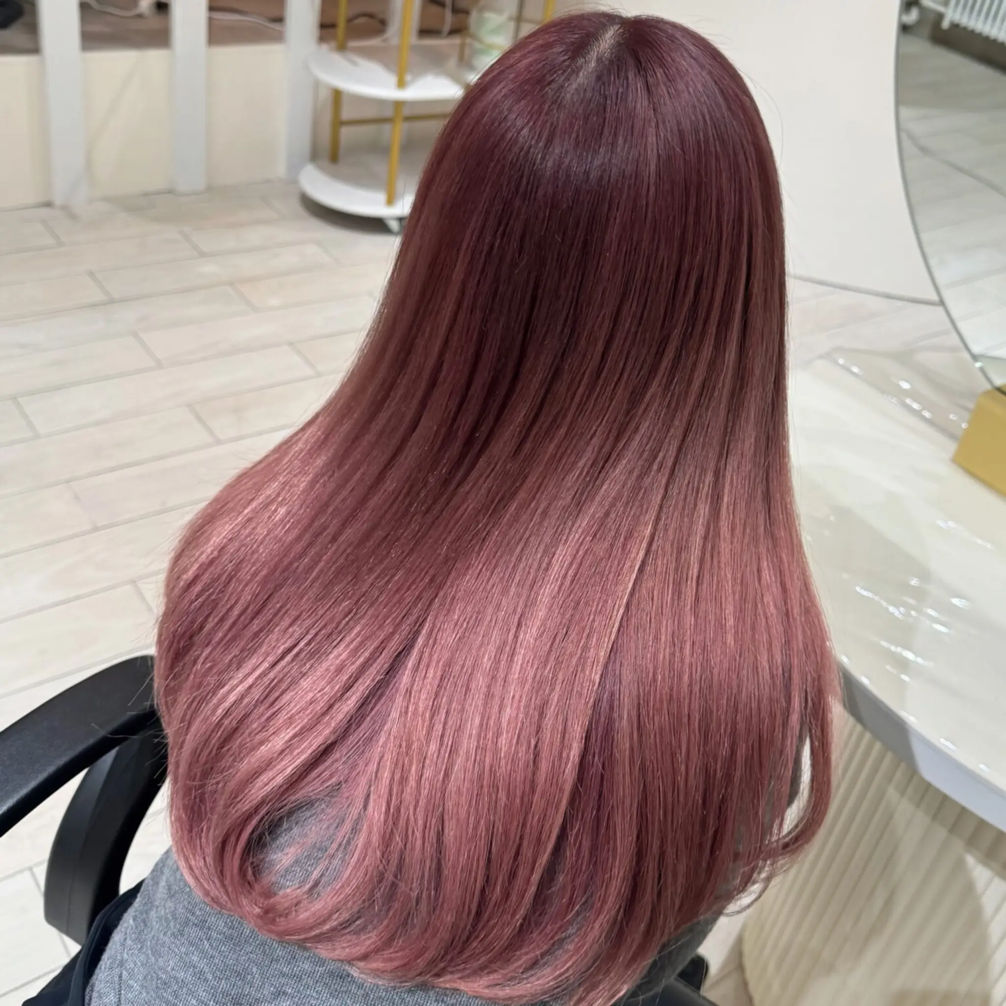 Long, sleek hairstyle with a beautiful ombre transition from rich rose gold at the roots to soft pink at the tips. The hair is straight and glossy, creating an elegant and modern look.