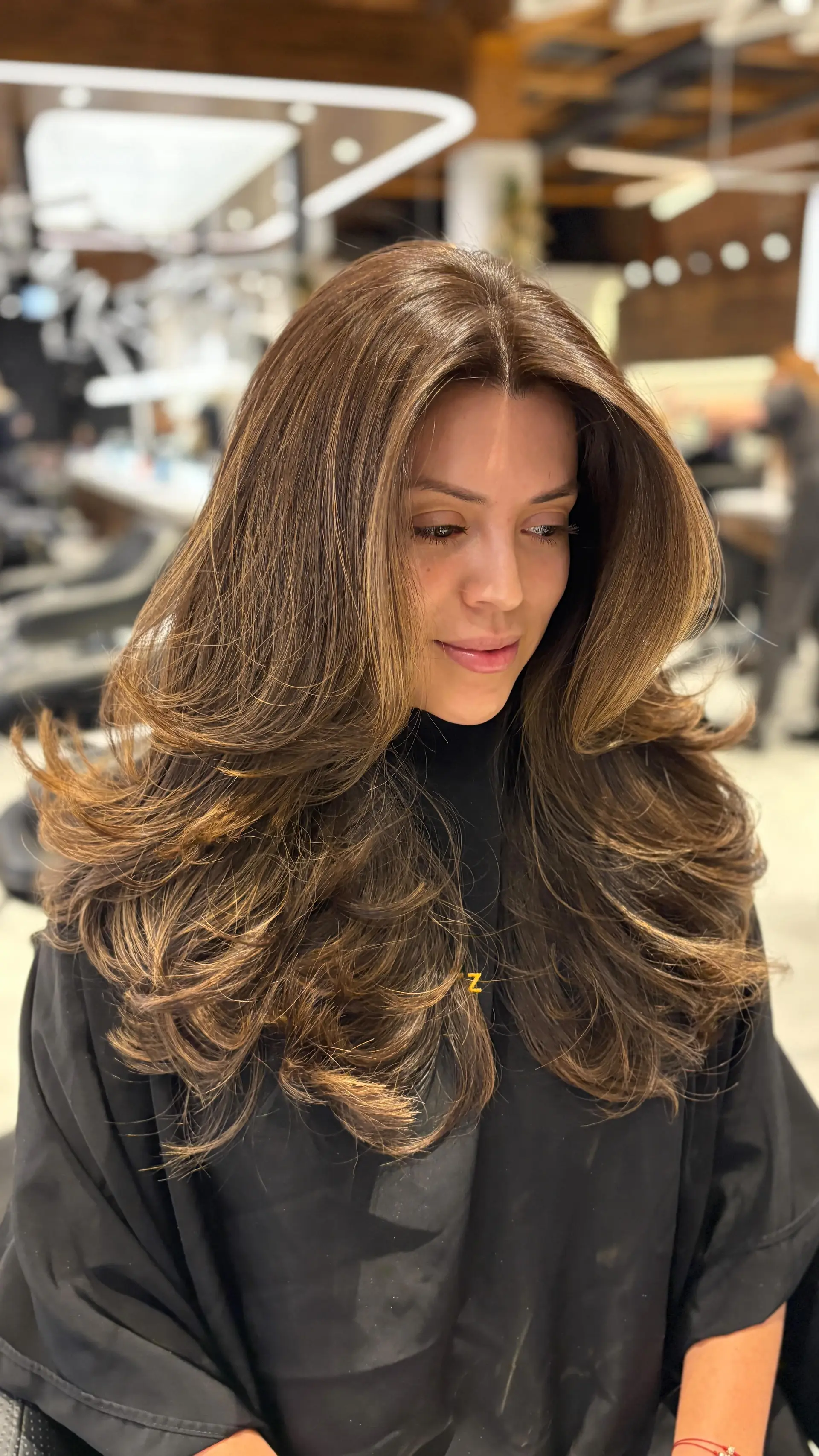 A glamorous, voluminous blowout featuring dramatic flipped ends and face-framing layers on long brunette hair. 1