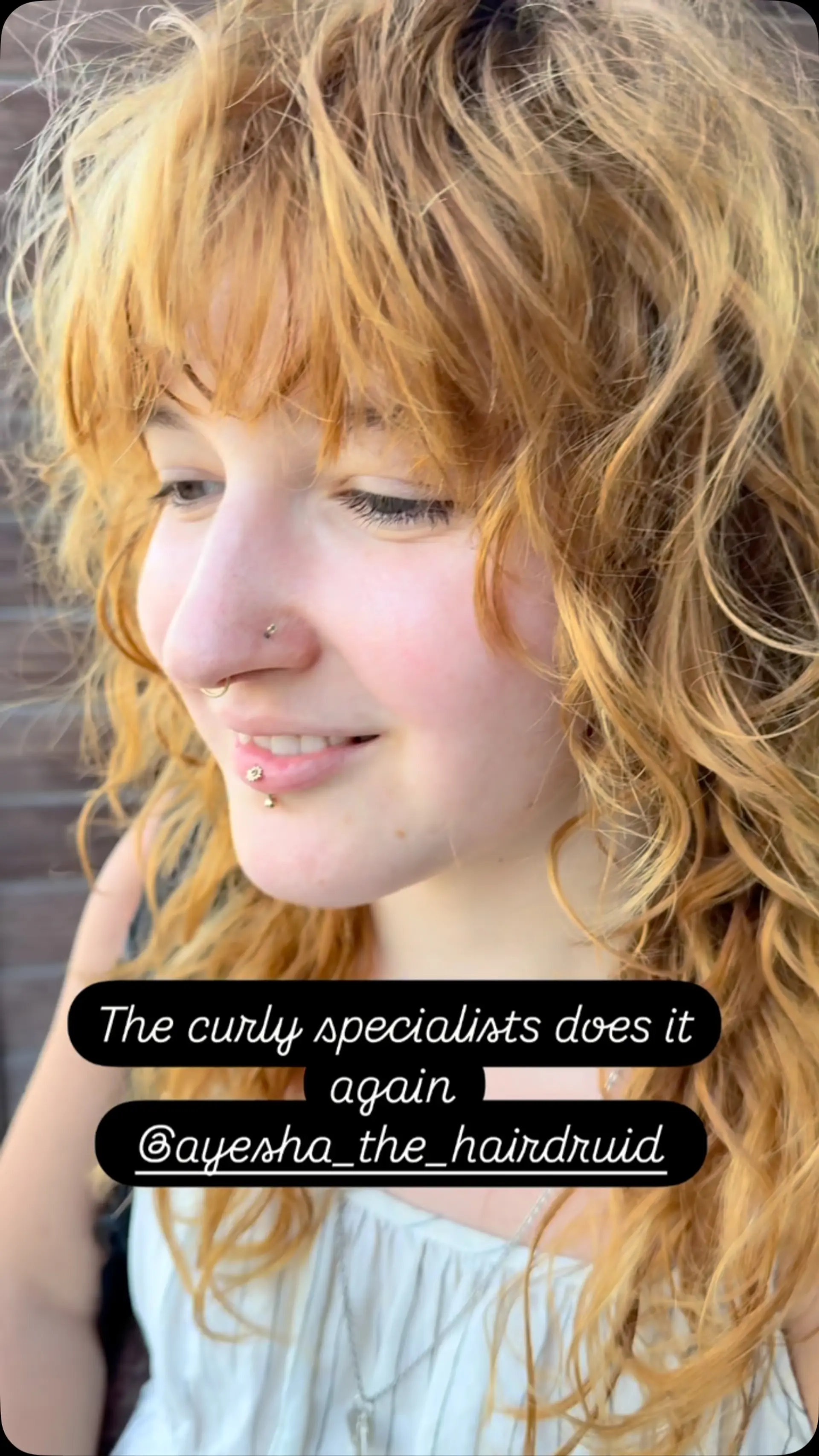 A textured curly shag cut in a warm golden blonde shade featuring soft fringe bangs. 1