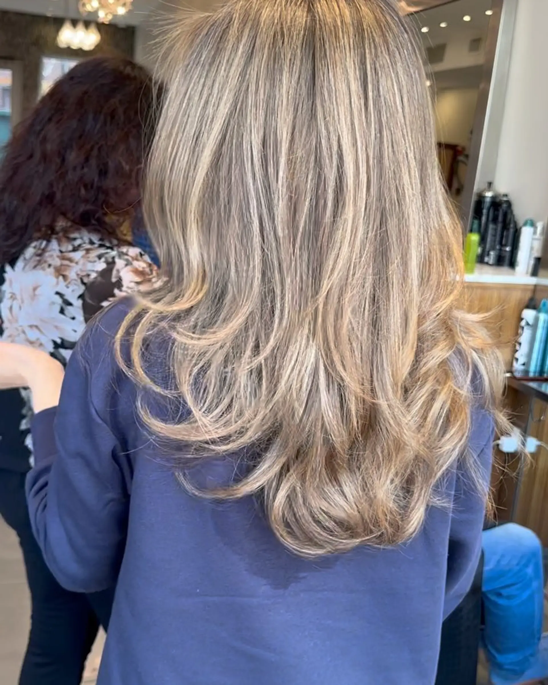 Long layered hair featuring blended ash and beige blonde highlights, styled in a voluminous blowout with softly flipped ends. 1