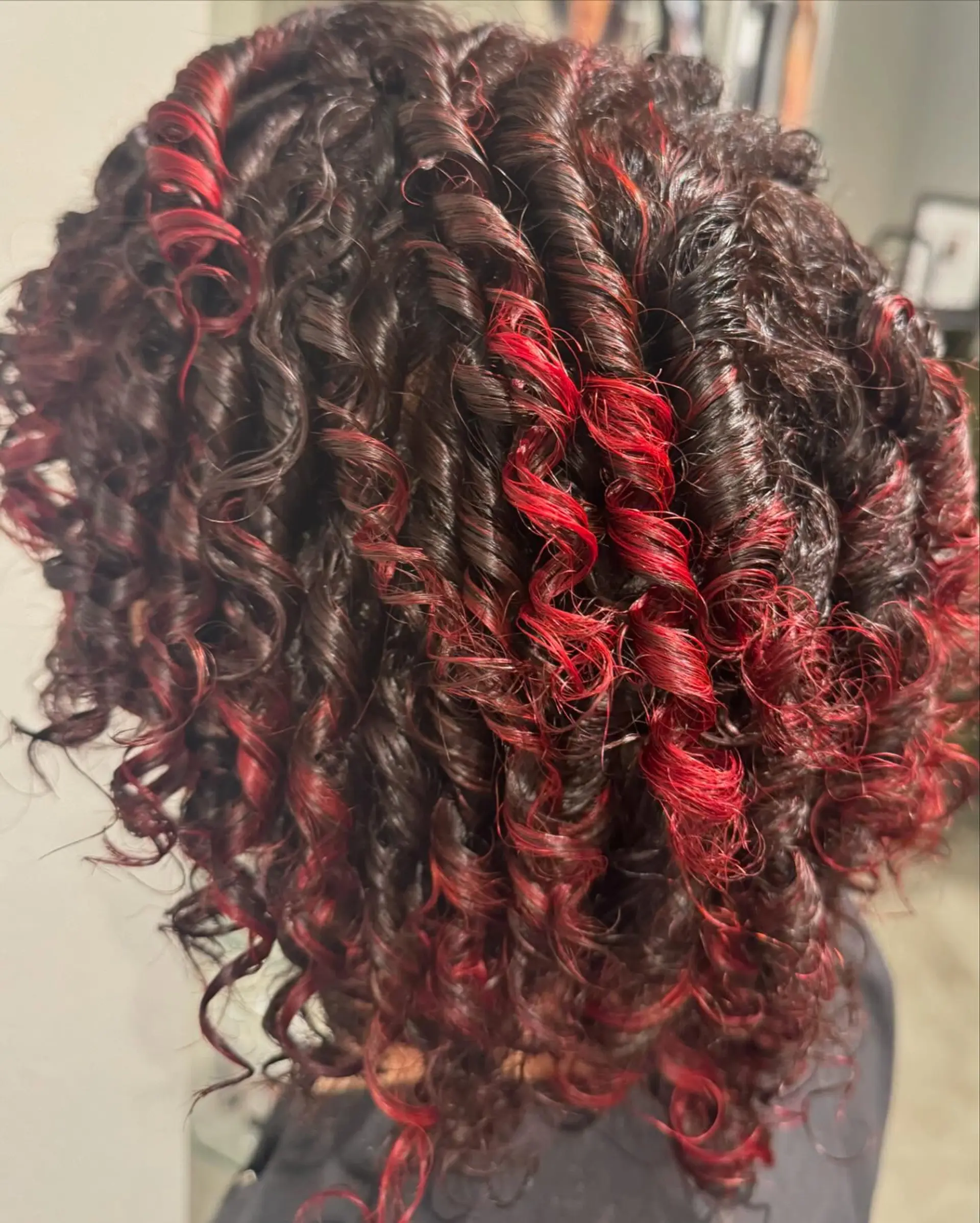 Glossy, defined spiral curls featuring vibrant fiery red ribbons woven through deep black coils. 1