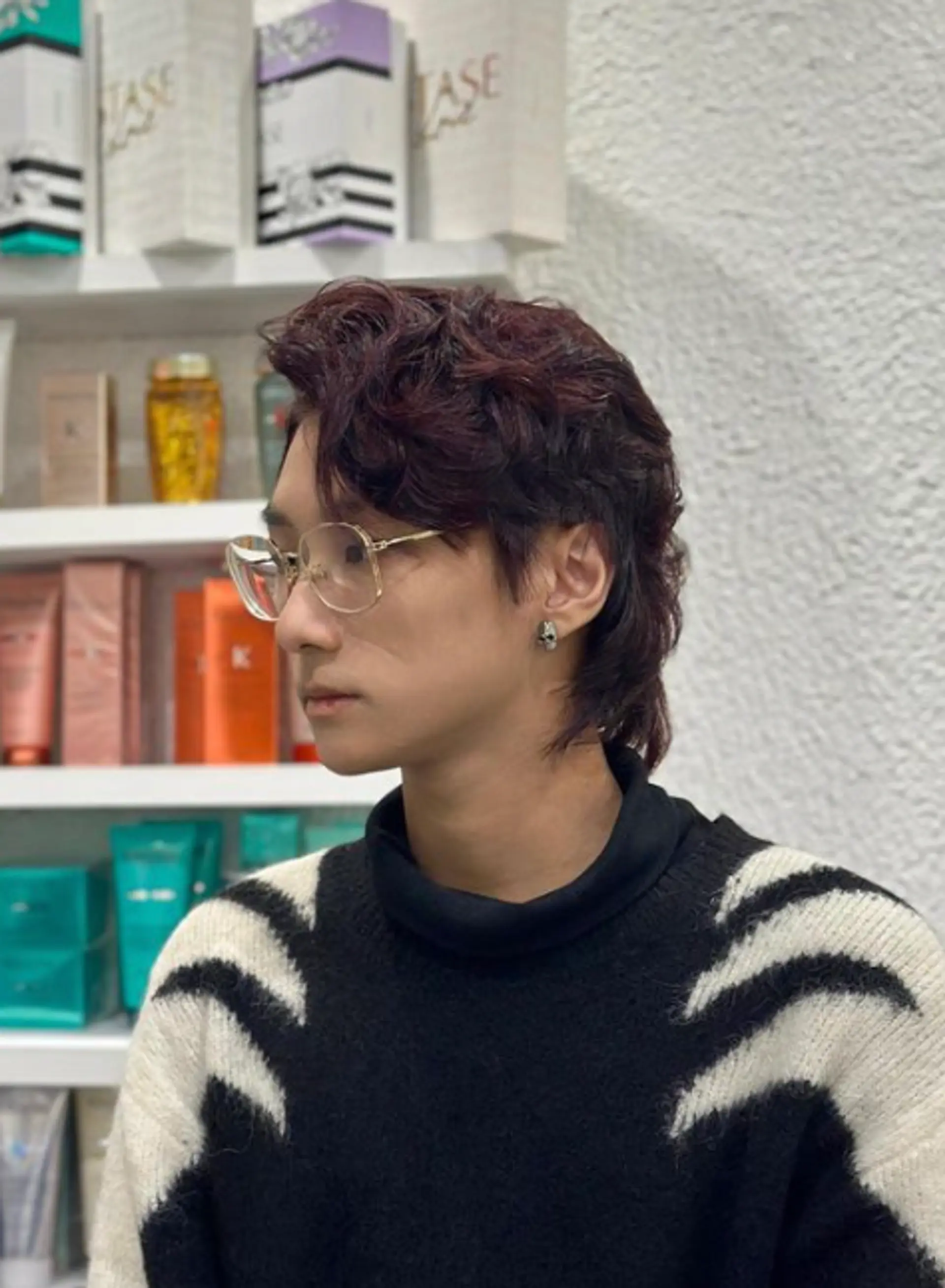 Medium-length wavy hair cascading in a retro mullet-inspired look with shorter, layered sides that frame the face and provide volume with dark brown color. 1