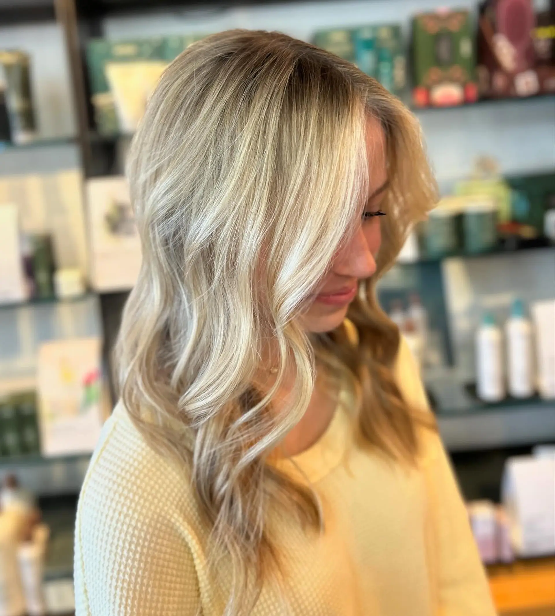 Bright beach blonde balayage cut with gentle layers and styled in loose, effortless waves. 1