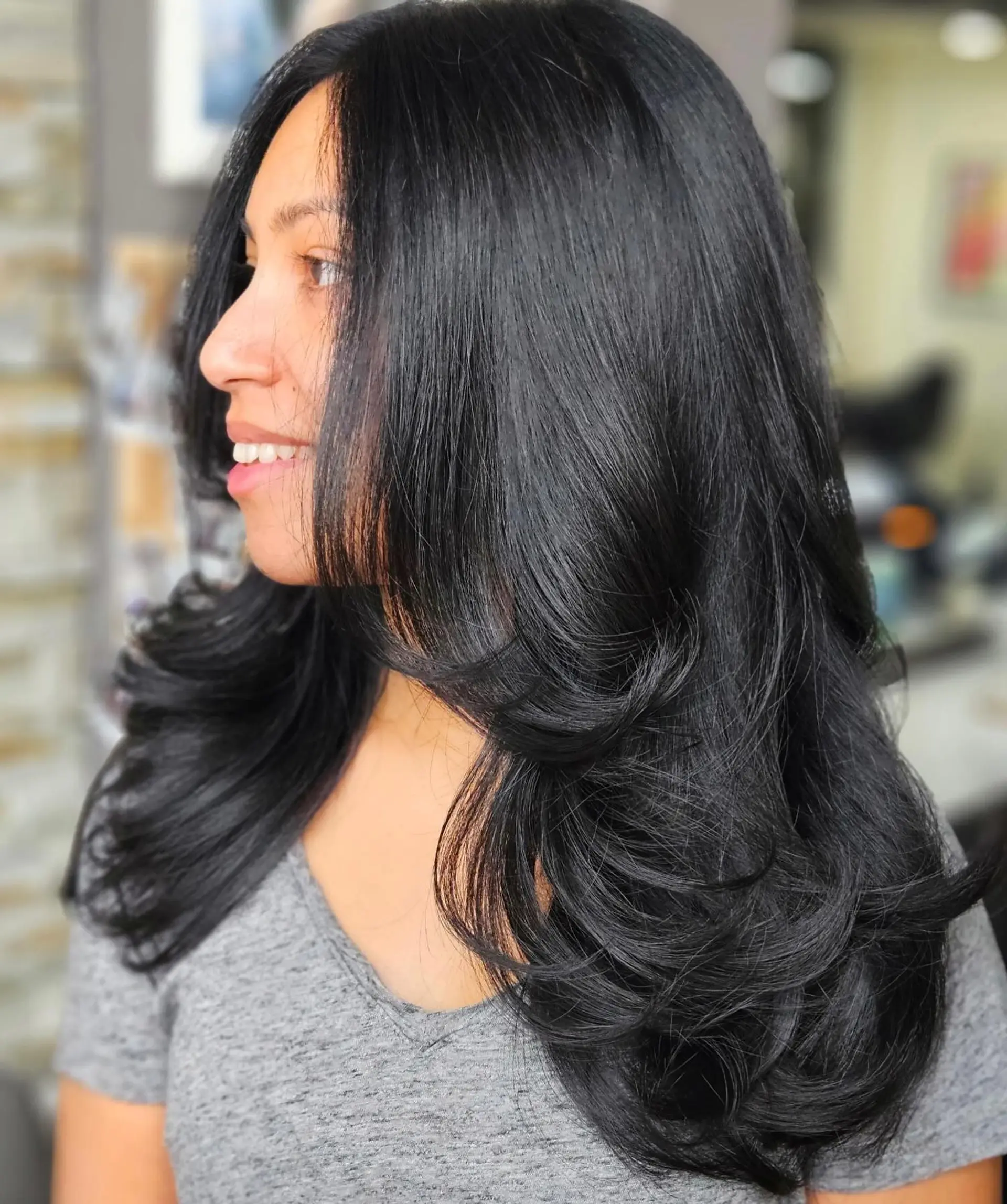 Glossy, jet black long hair styled with soft face-framing layers and curled-under bouncy ends. 1