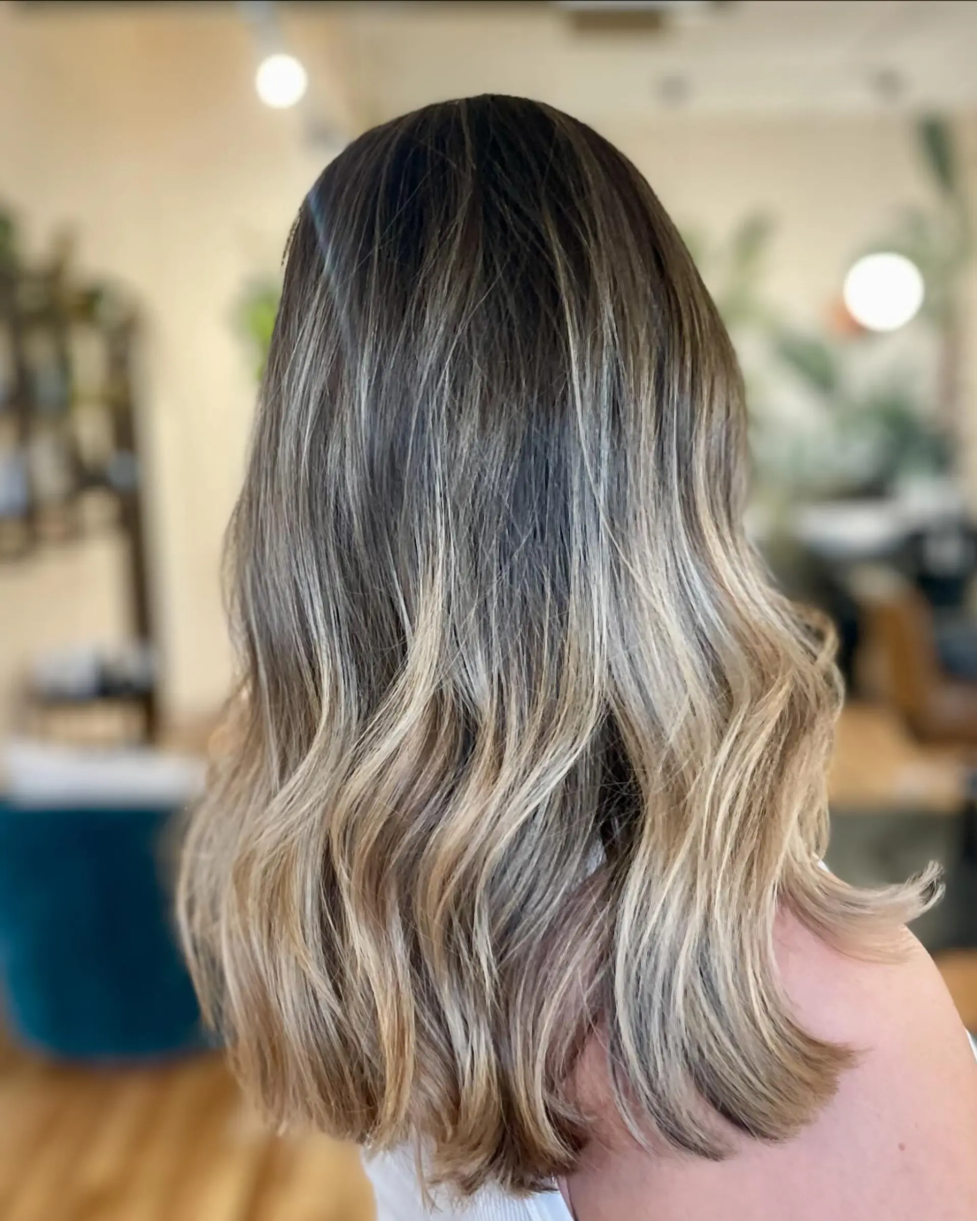 Medium-length wavy hair featuring finely blended ash and golden babylights on a deep natural base. 1