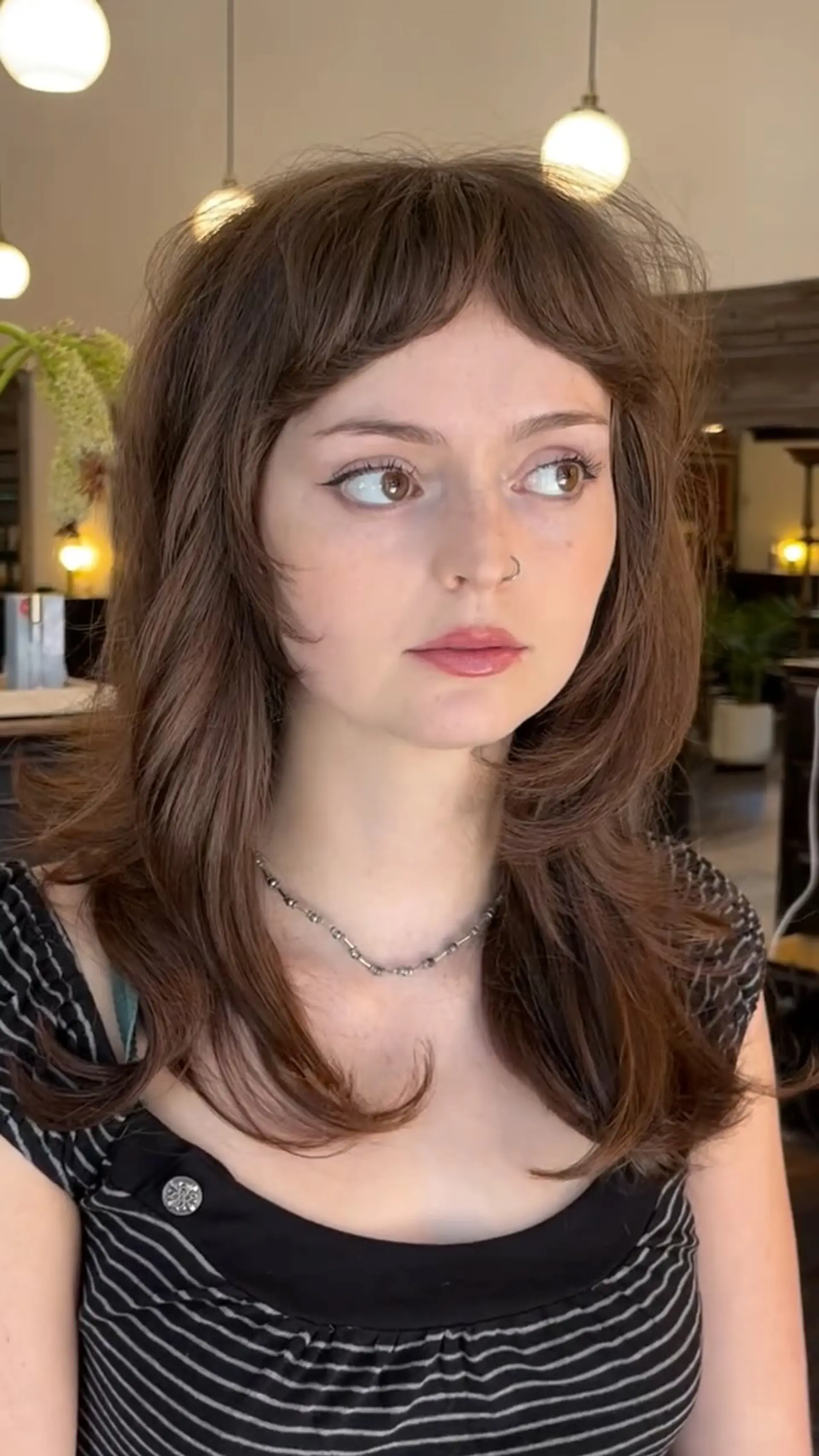 A medium-length textured brunette shag featuring soft arched micro bangs and tiered, face-framing layers. 1