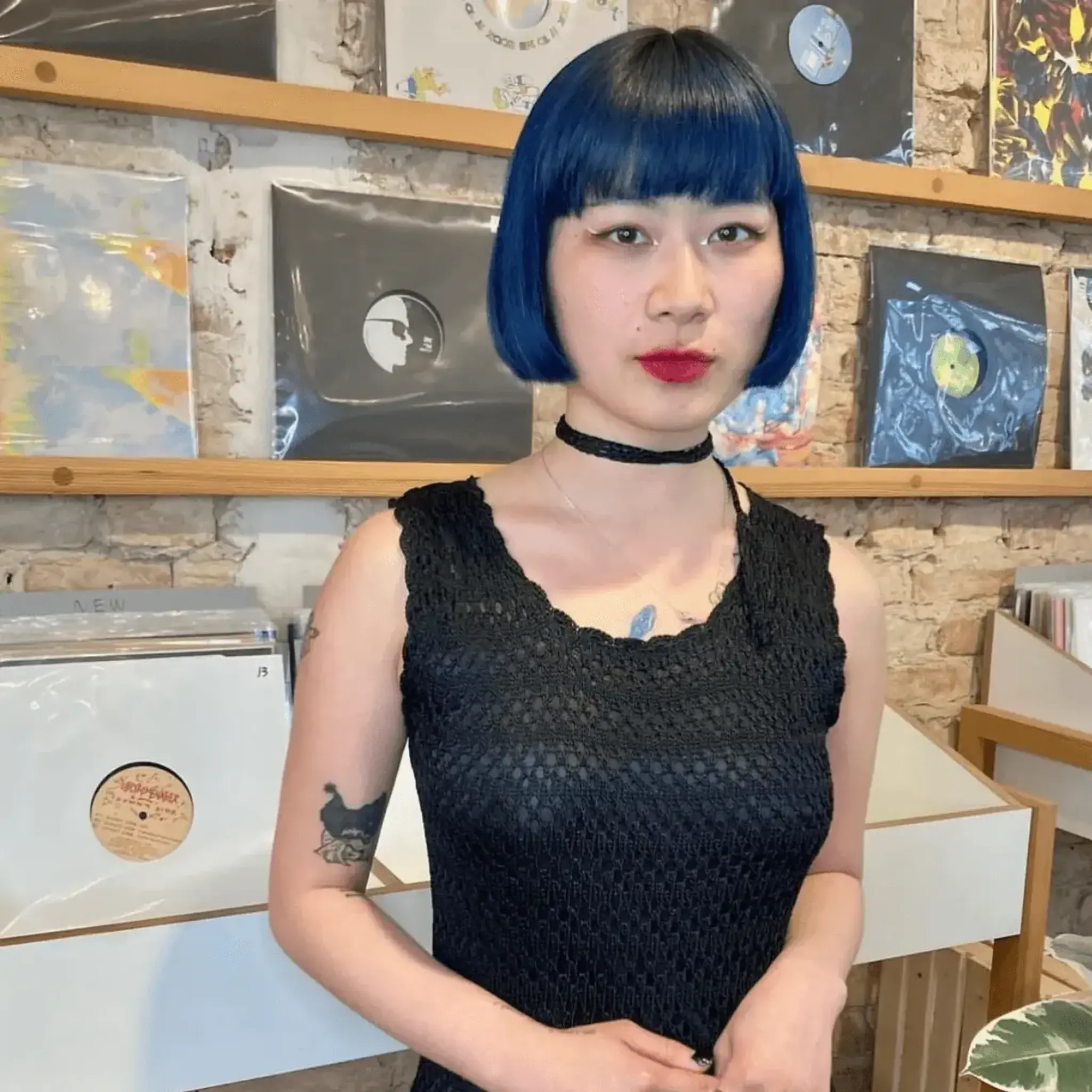 Bold and edgy short bob haircut in electric blue with blunt bangs. The hair is straight and meticulously styled for a sleek appearance.