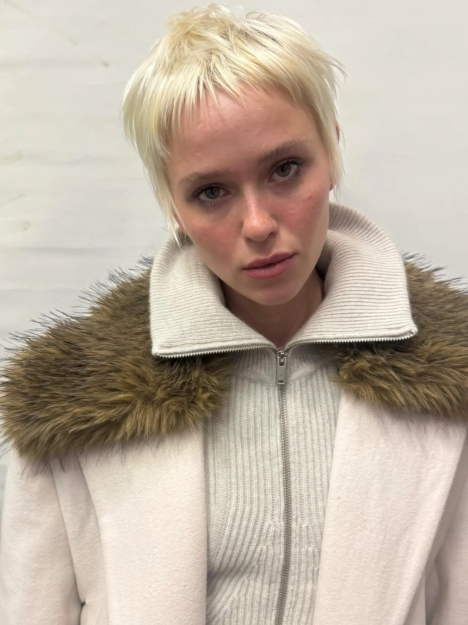 A textured pixie cut with choppy layers and short, blunt baby bangs, designed to frame the face with a contemporary, edgy feel. 1