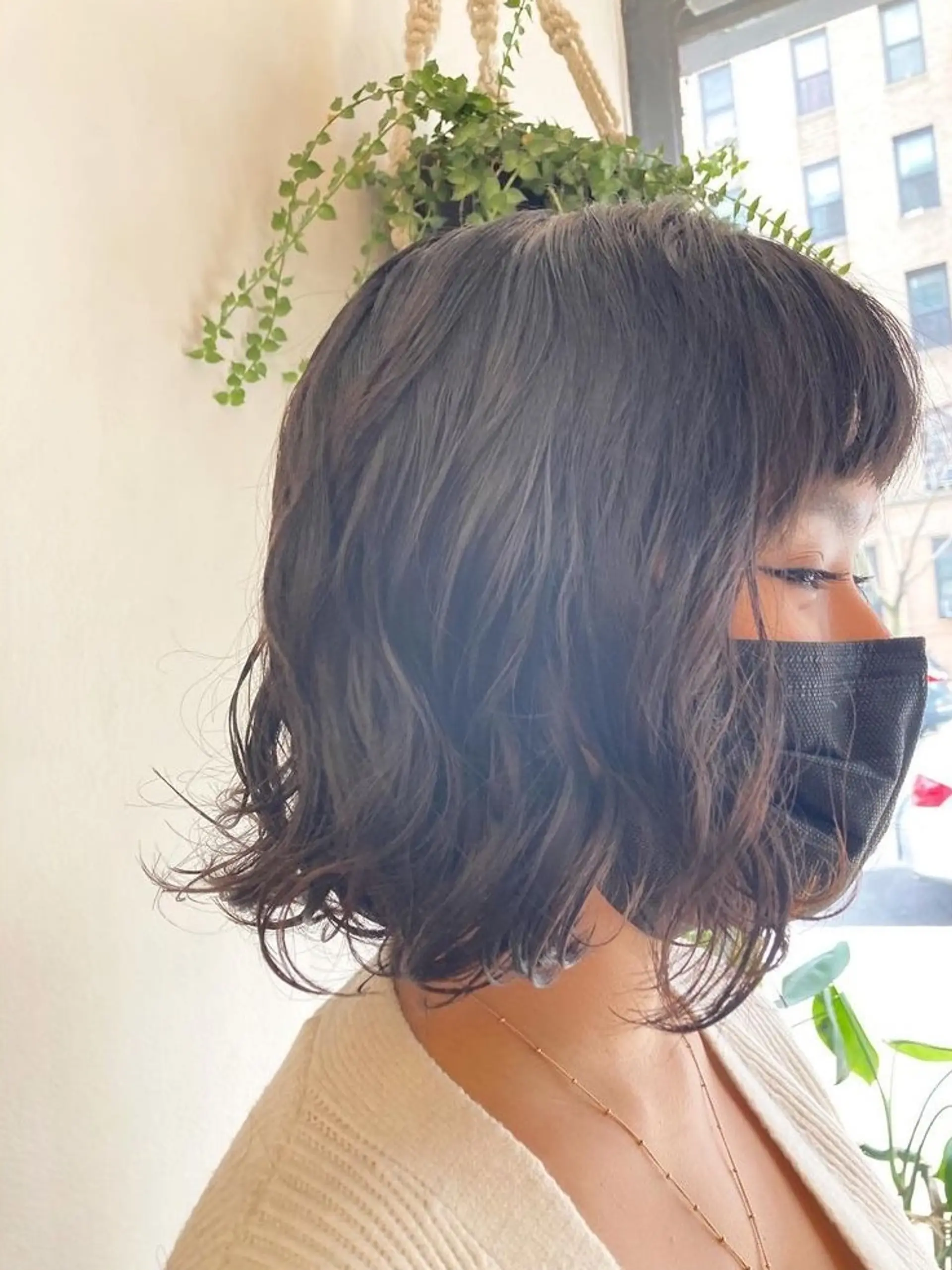 A trendy chin-length bob with soft, natural waves and blunt bangs, giving a fresh and modern look with dark brown hair. 1