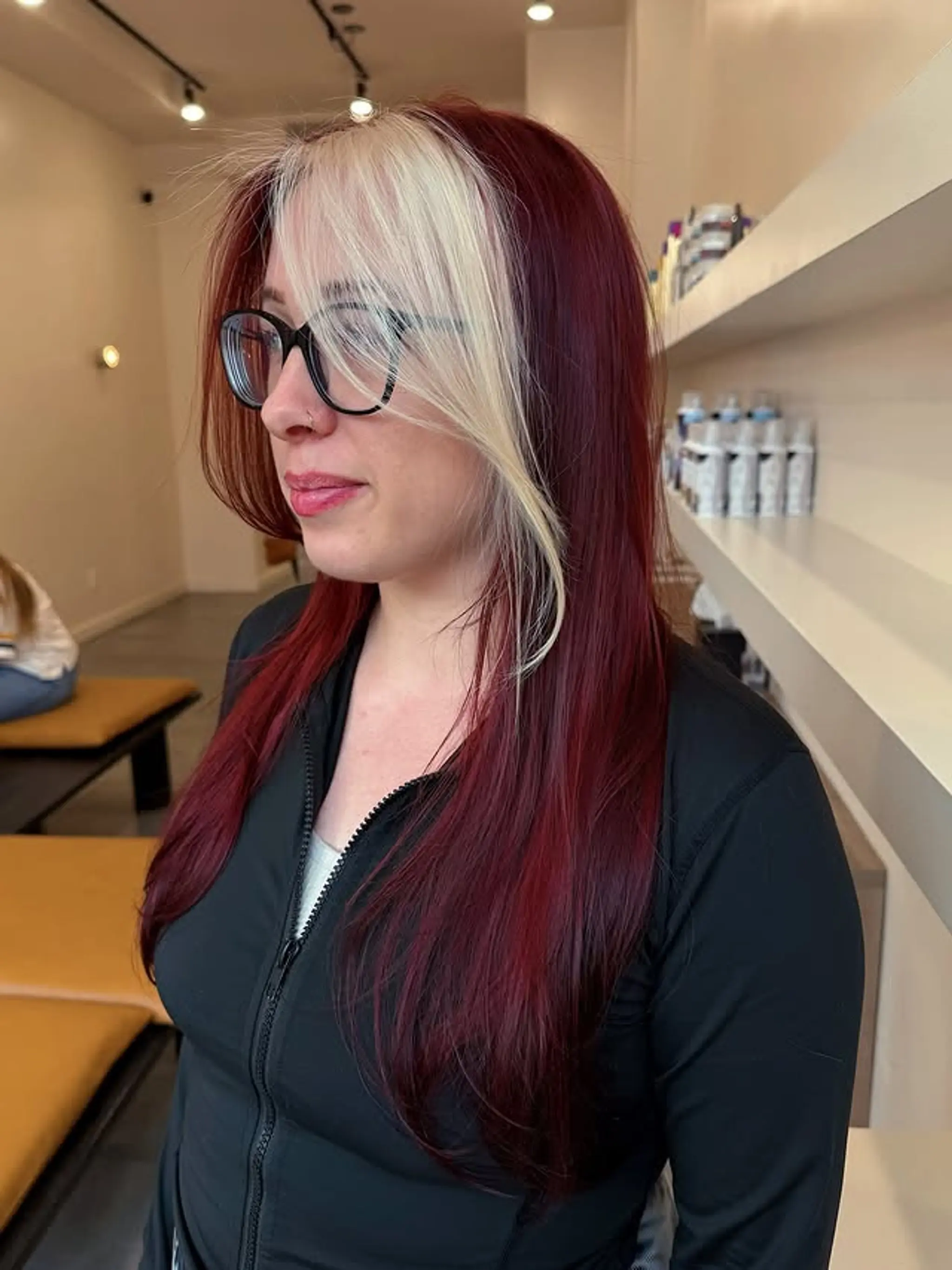 Long, layered hairstyle with a bold split dye effect, featuring a red base color and a blonde money piece.