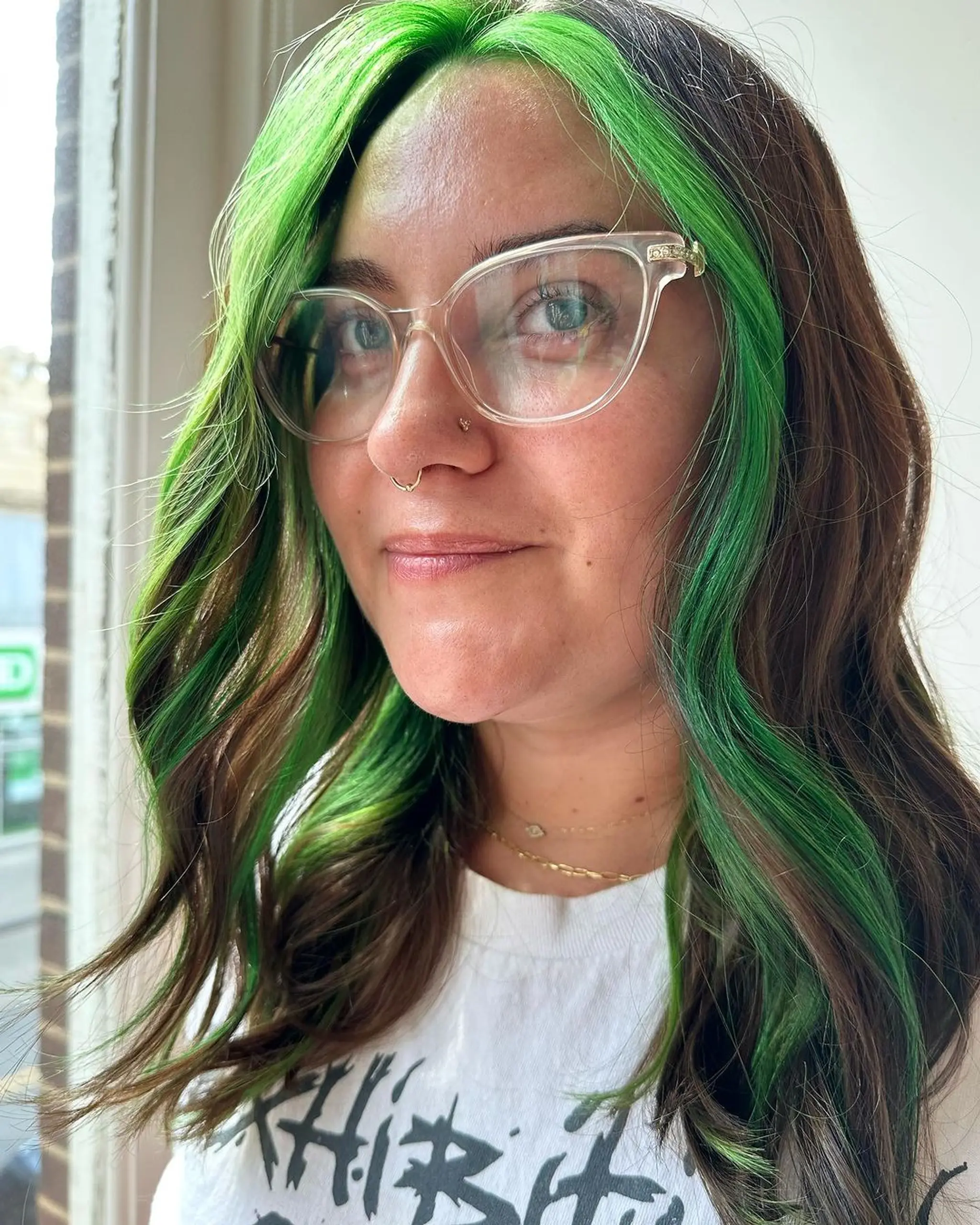 Medium-length wavy hair with face-framing green and brown colors, featuring a two-tone design with natural waves.