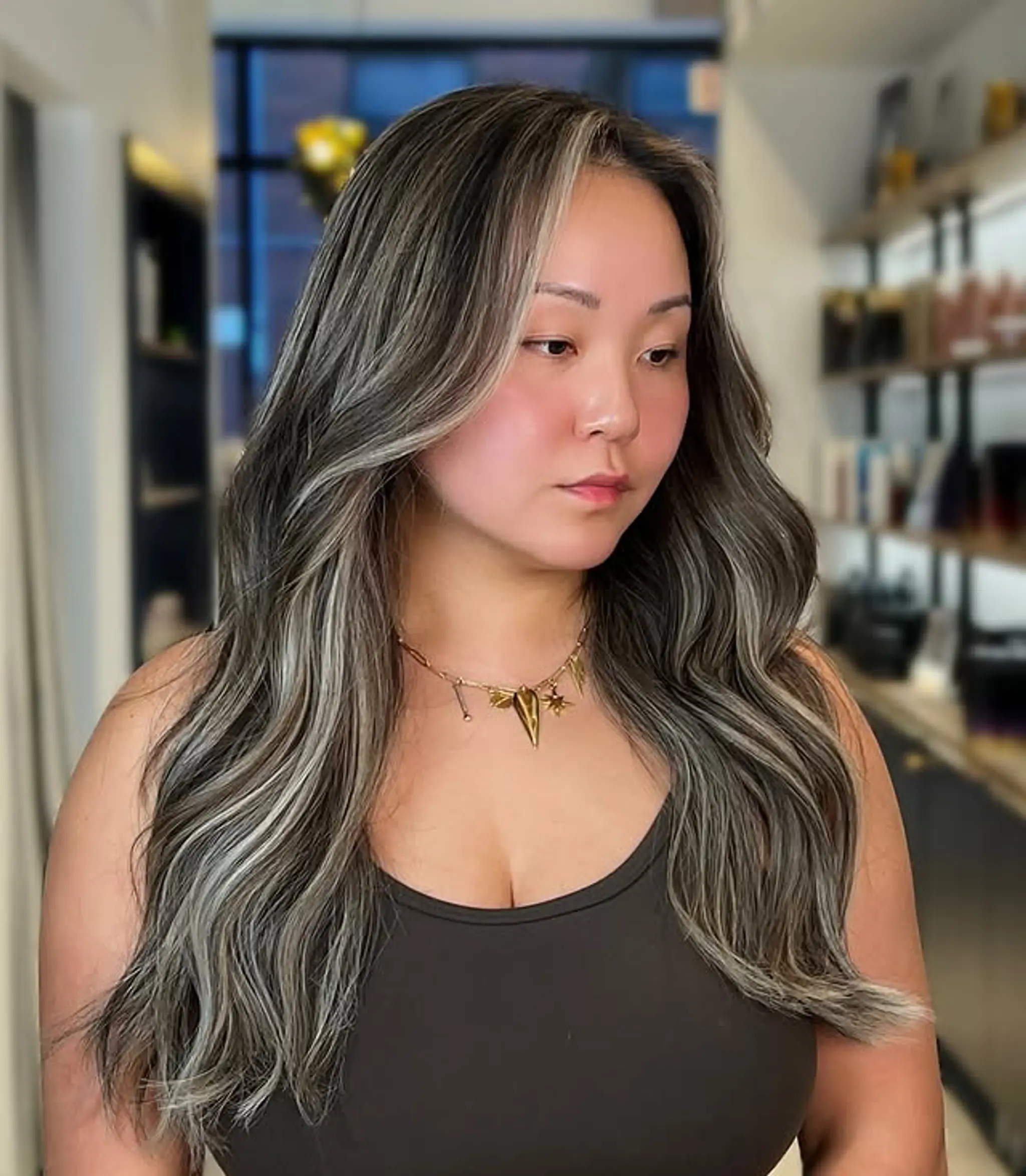 Long, wavy hair with face-framing silver highlights to add a trendy money piece effect.