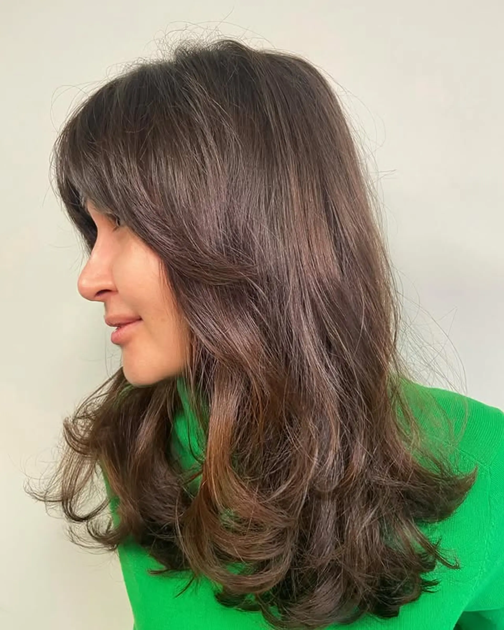 This hairstyle features long, flowy layers with face-framing curtain bangs for a vintage 70s feel. 1