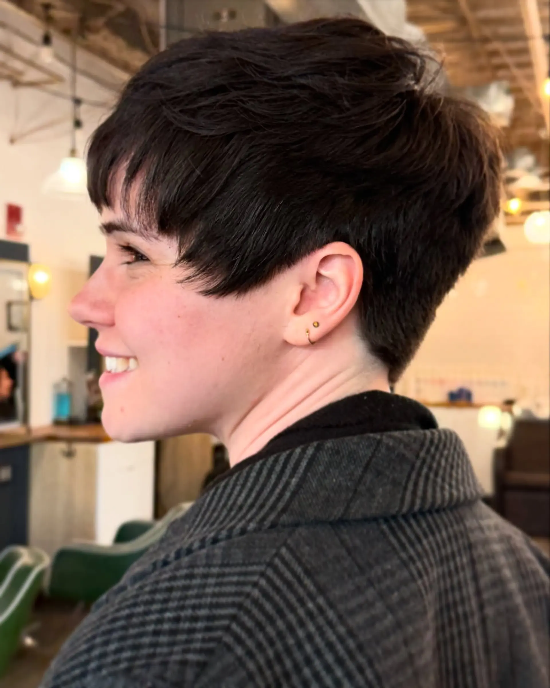 A textured dark brunette pixie cut featuring tapered sides, soft crown volume, and a piecey cropped fringe. 1