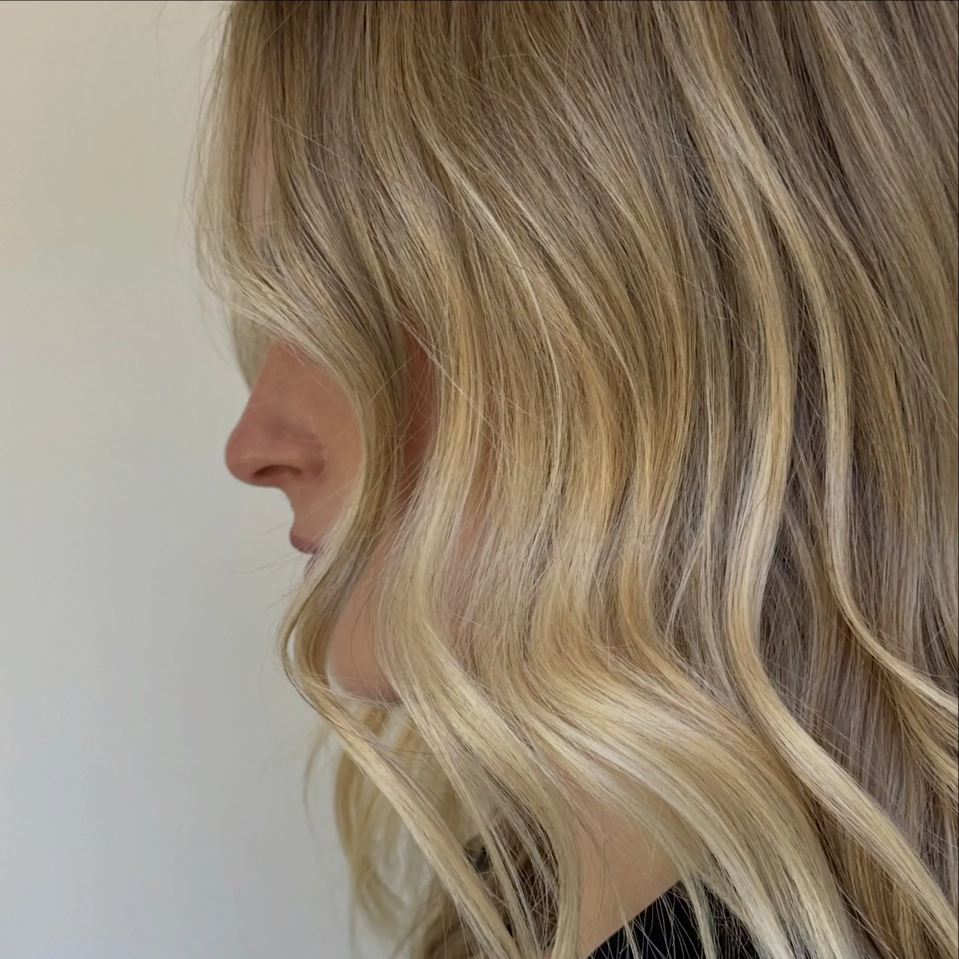 Medium-length wavy hair featuring a seamless, multidimensional lived-in blonde balayage with face-framing pieces. 1