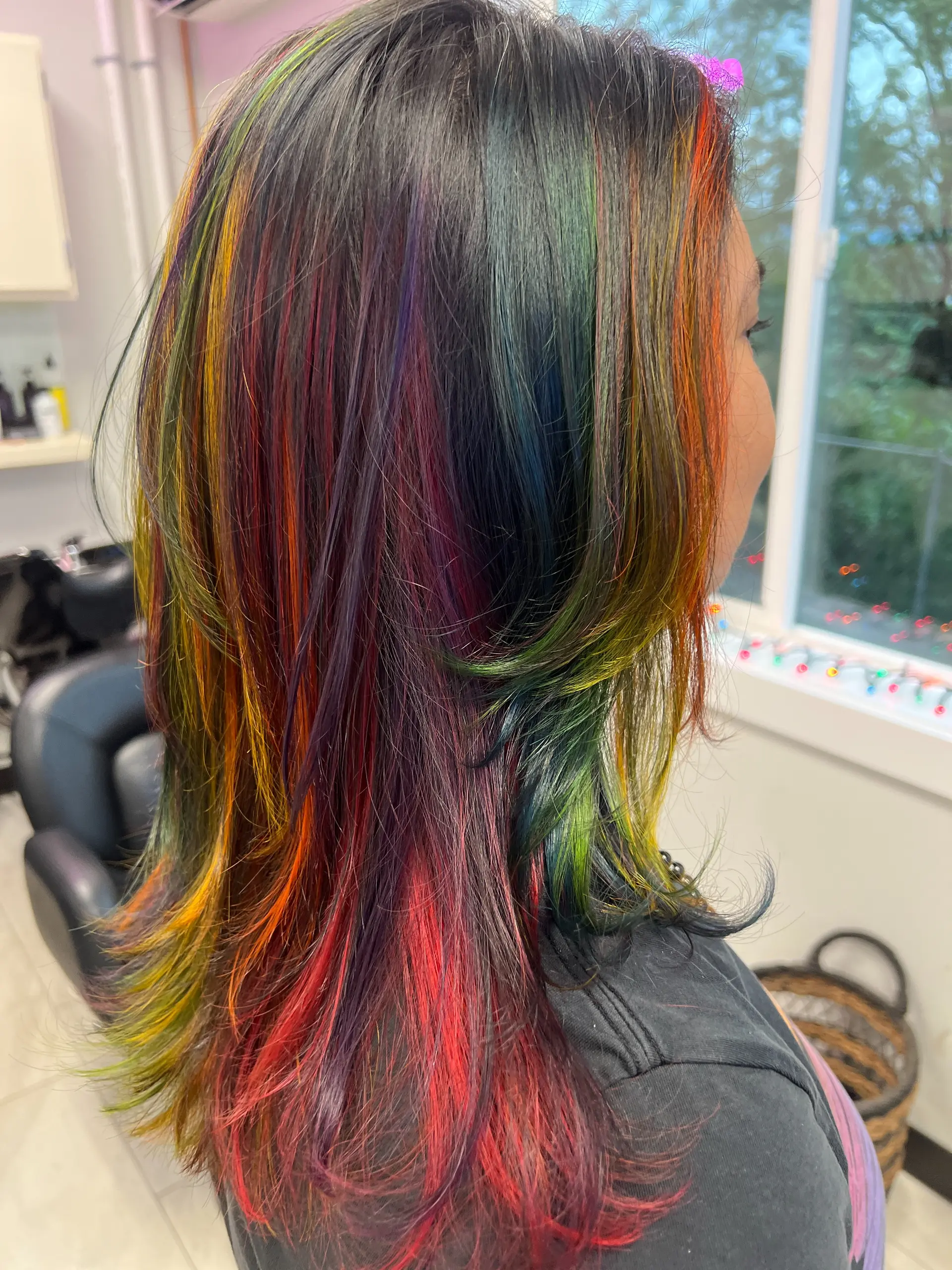 Medium-length dark hair with vibrant multicolored rainbow highlights and flipped layered ends. 1