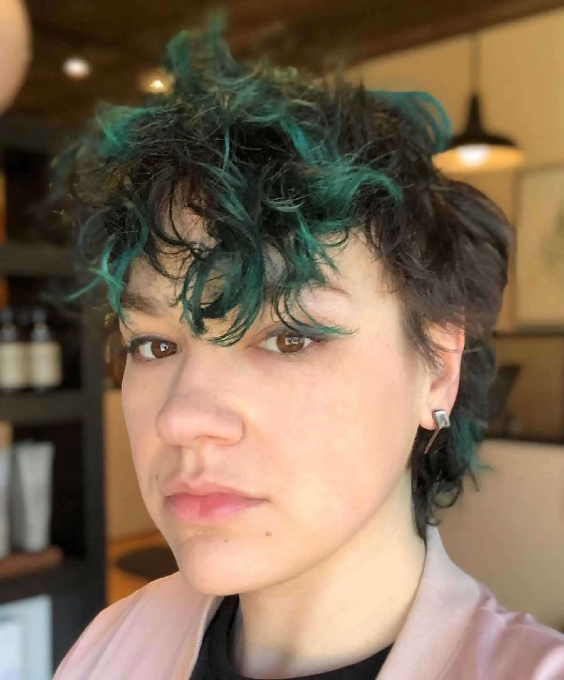 A short, textured pixie cut with vibrant teal highlights. 1