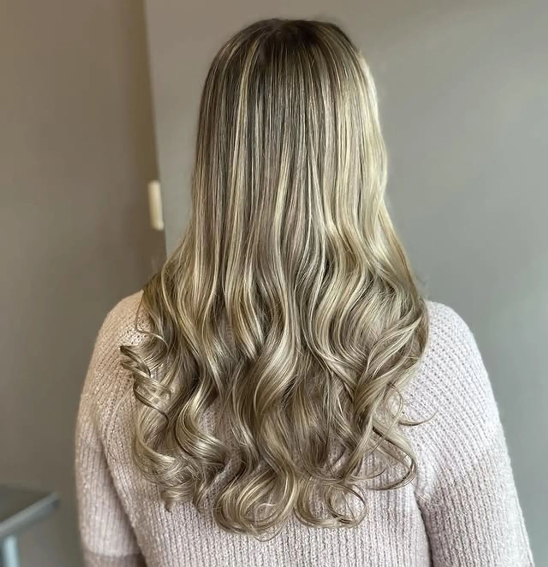 A long, layered hairstyle with soft waves and an ash blonde balayage. 1