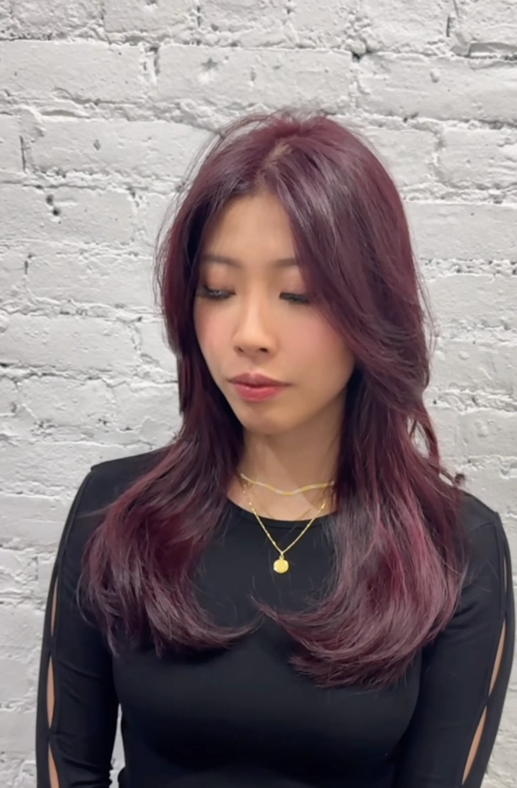 Long, wavy hairstyle in a deep plum shade with soft layers and a middle part for face-framing elegance.