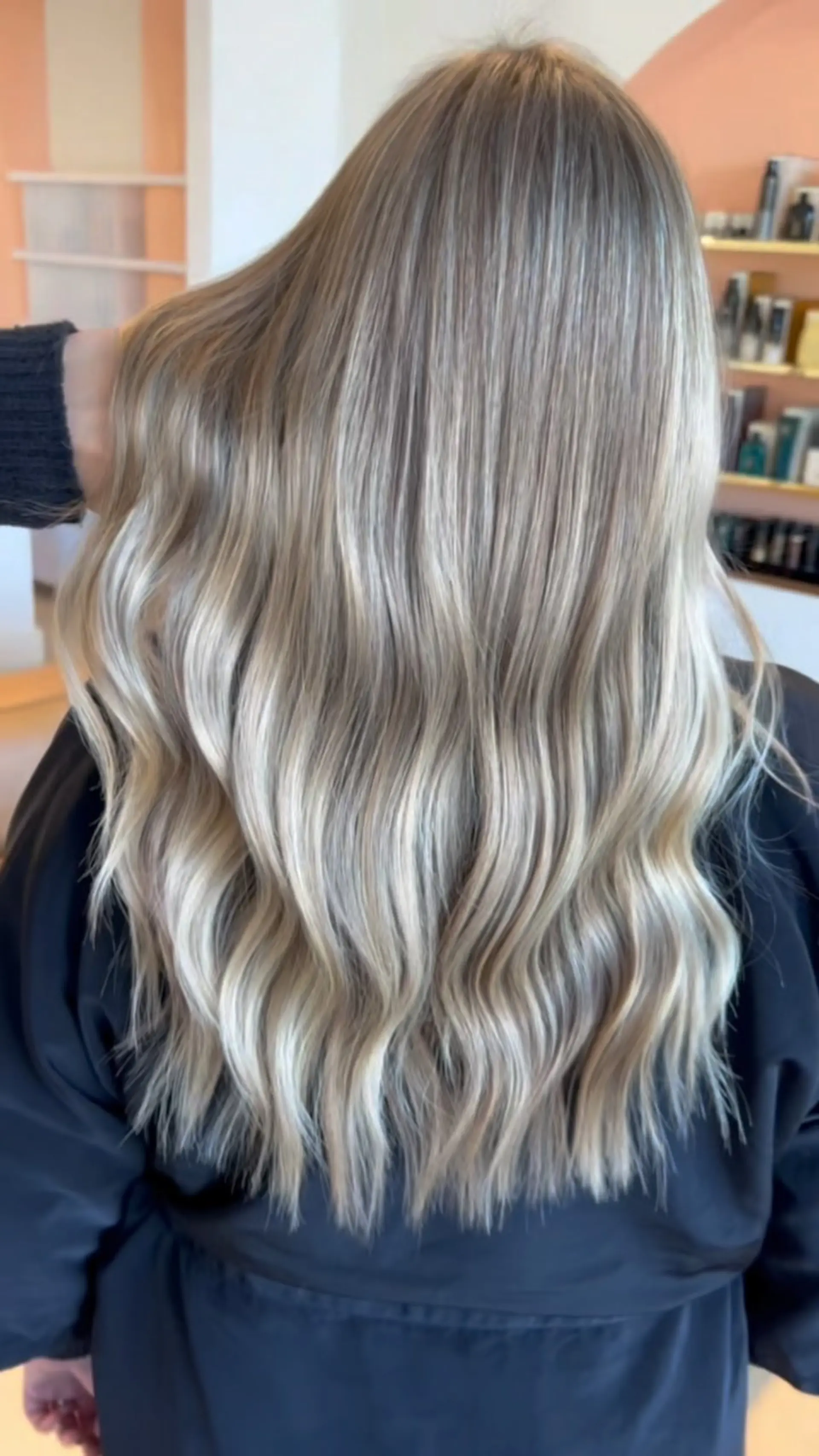 Long ash blonde hair featuring seamless dimensional balayage highlights styled in soft, relaxed waves. 1