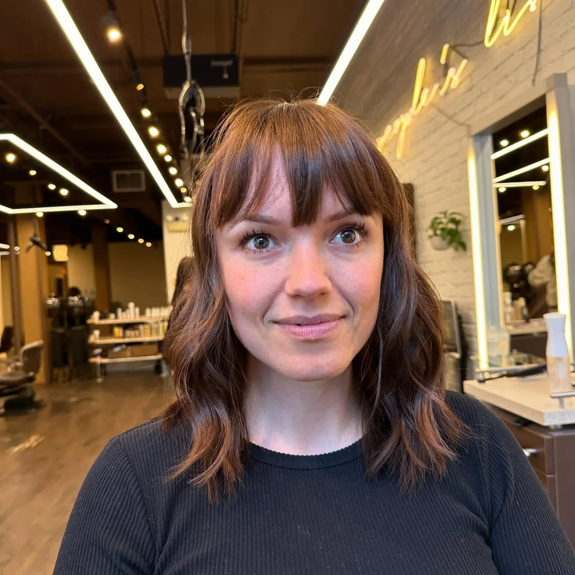 A trendy, medium-length wavy hairstyle with curtain bangs and soft layers. 2