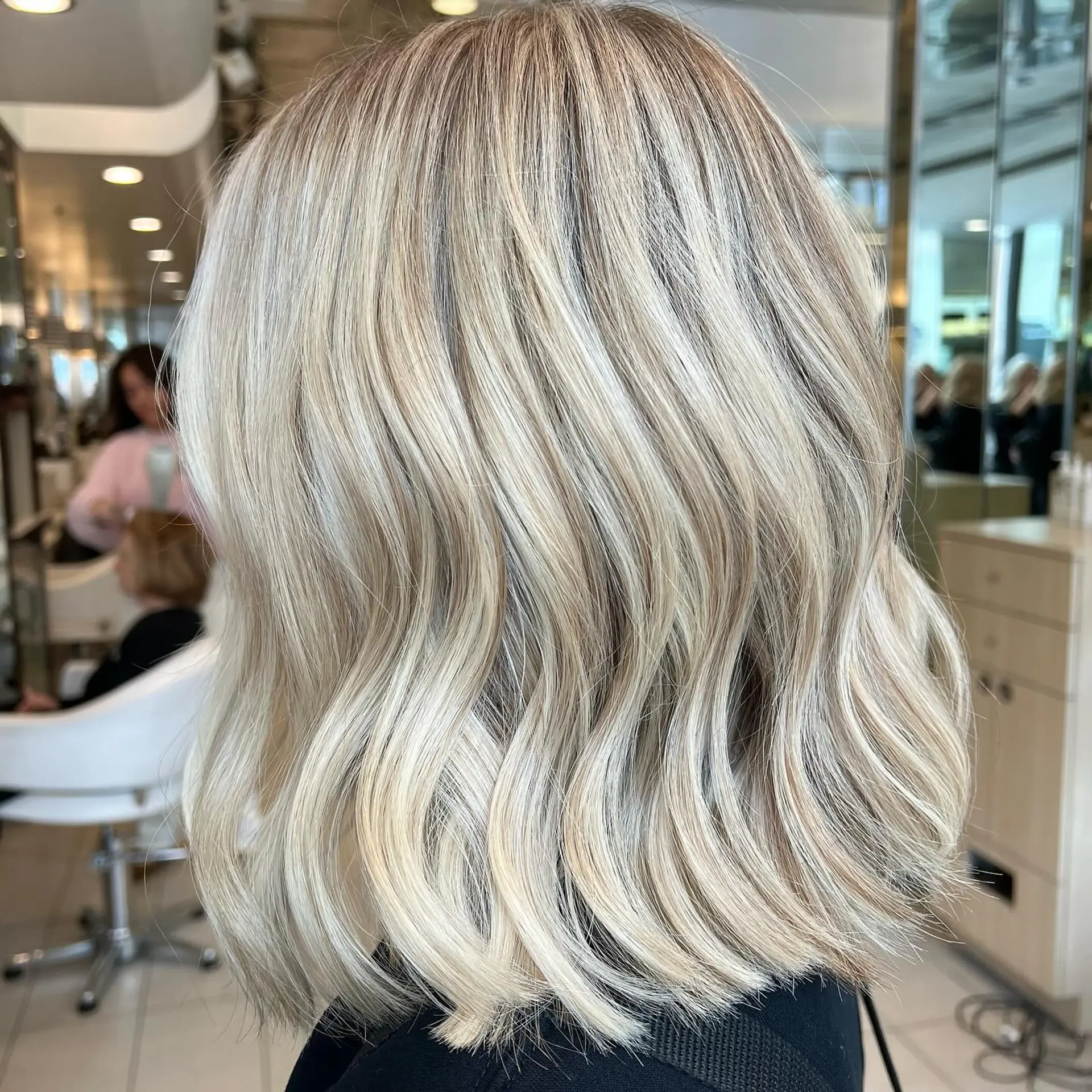 A bright blonde shoulder-length lob styled with soft, modern textured waves. 1