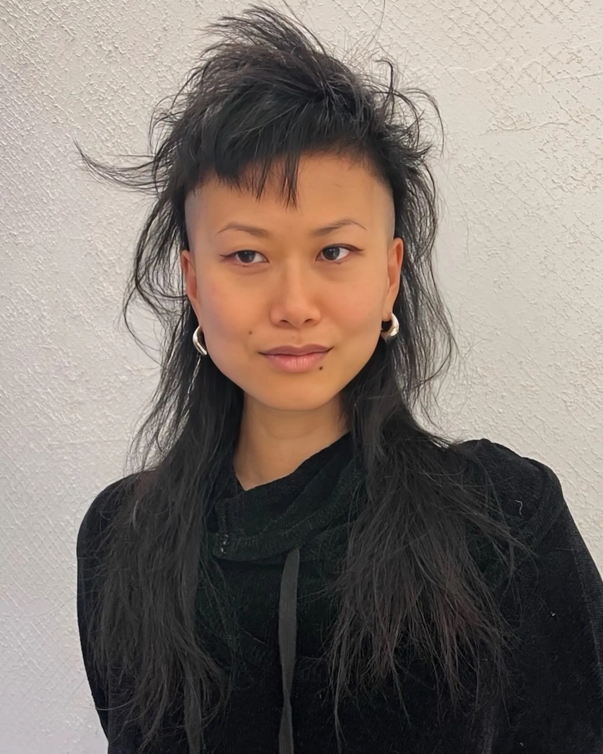 An edgy undercut mullet with bold, textured layers and a choppy fringe, styled for a versatile and modern look. 1