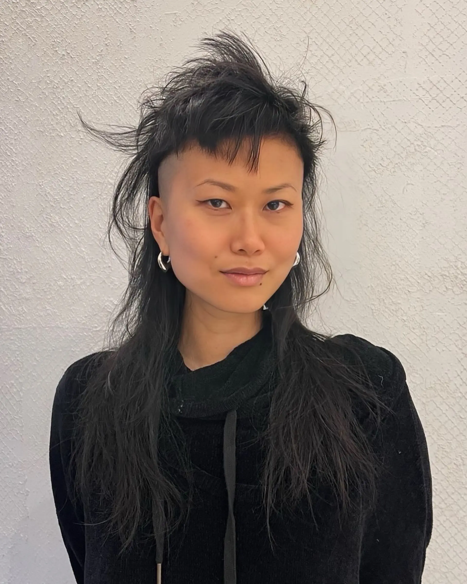 An edgy undercut mullet with bold, textured layers and a choppy fringe, styled for a versatile and modern look. 2